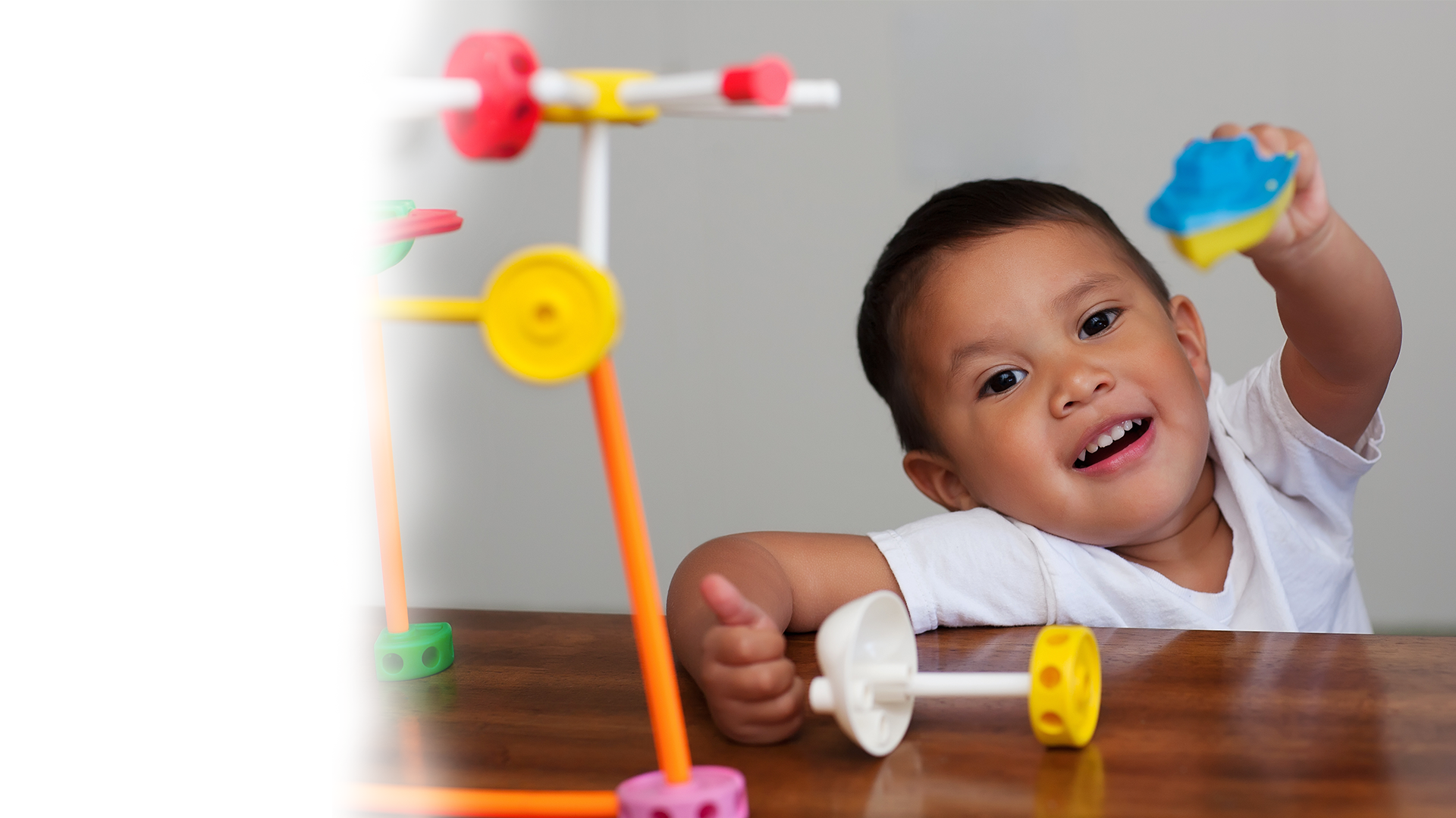 A young boy is sitting at a table playing with toys.