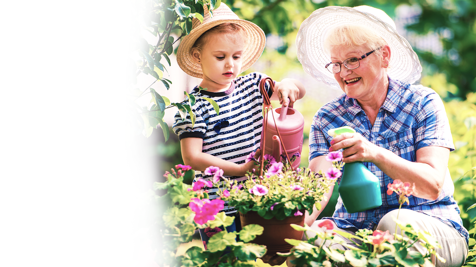 A woman and a child are watering flowers in a garden.