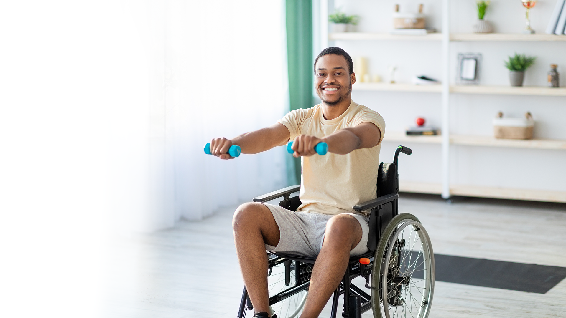 A man in a wheelchair is lifting dumbbells.