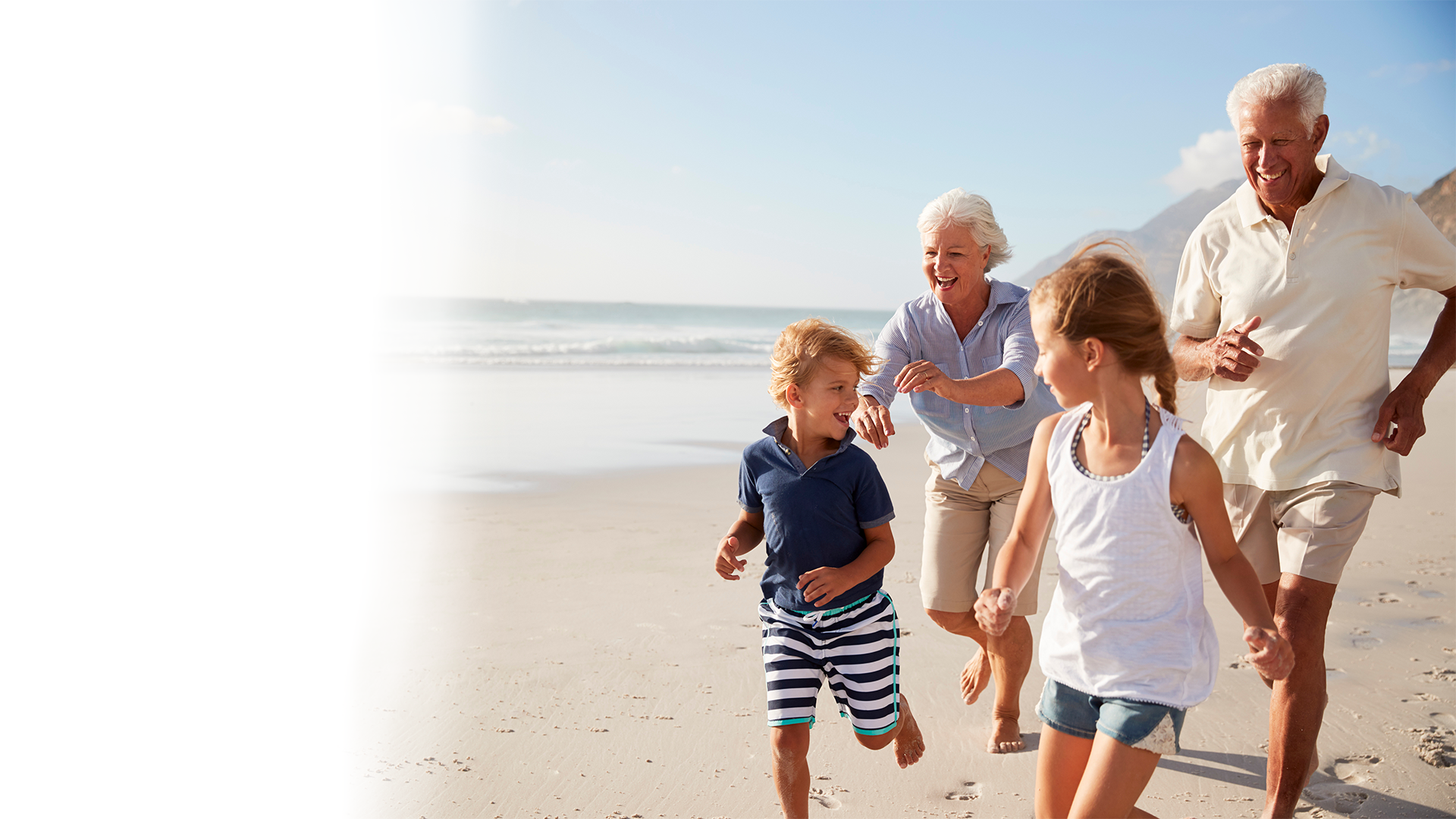 A family is running on the beach holding hands.