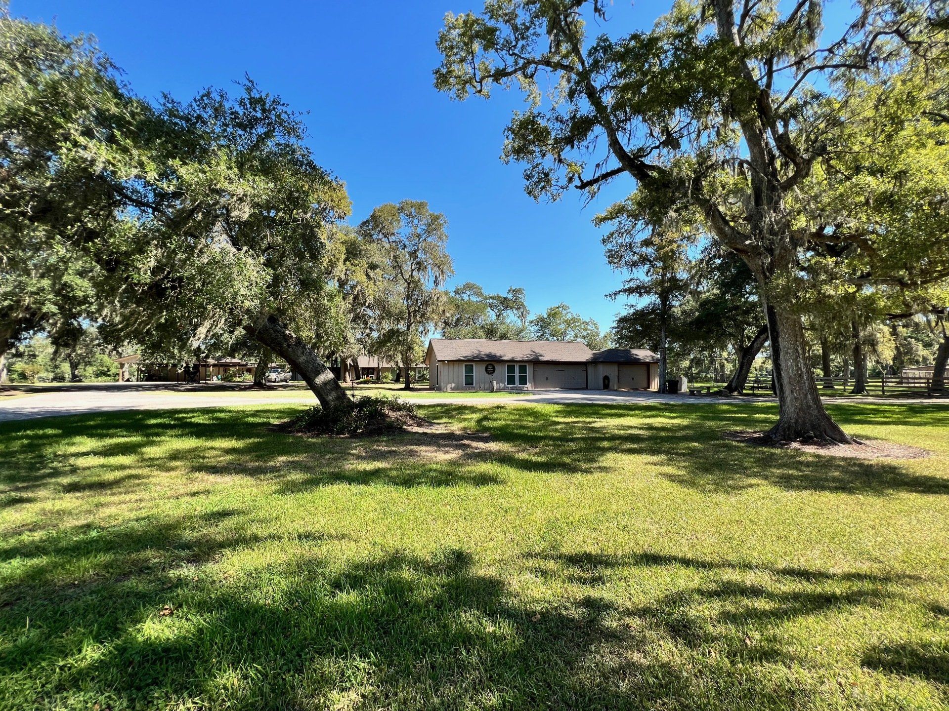 a house is sitting in the middle of a lush green field surrounded by trees .