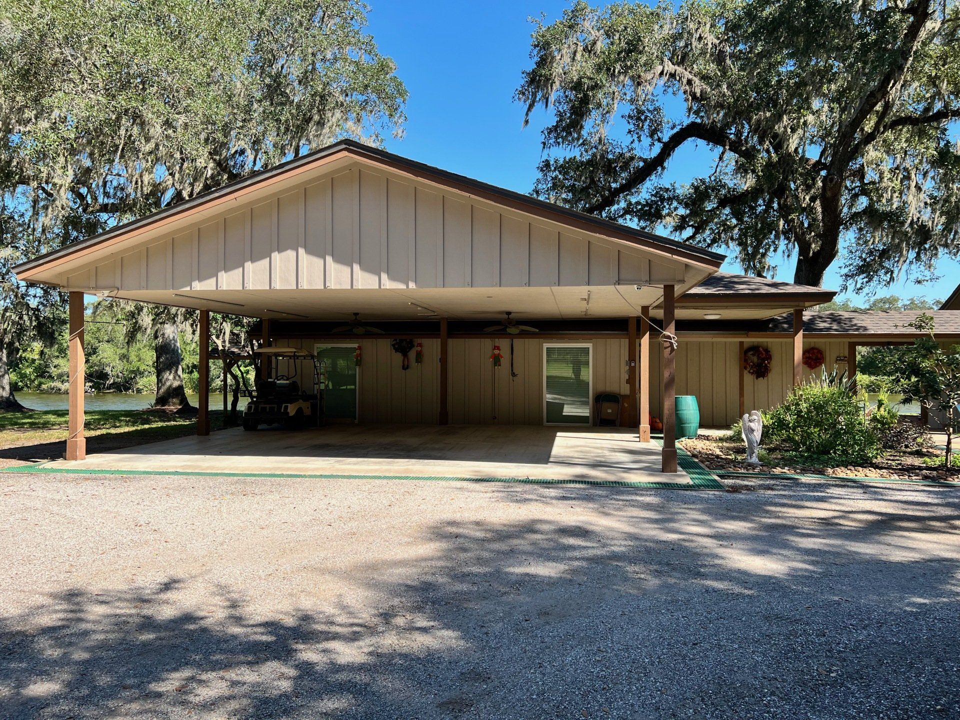 a house with a carport underneath it and trees in the background