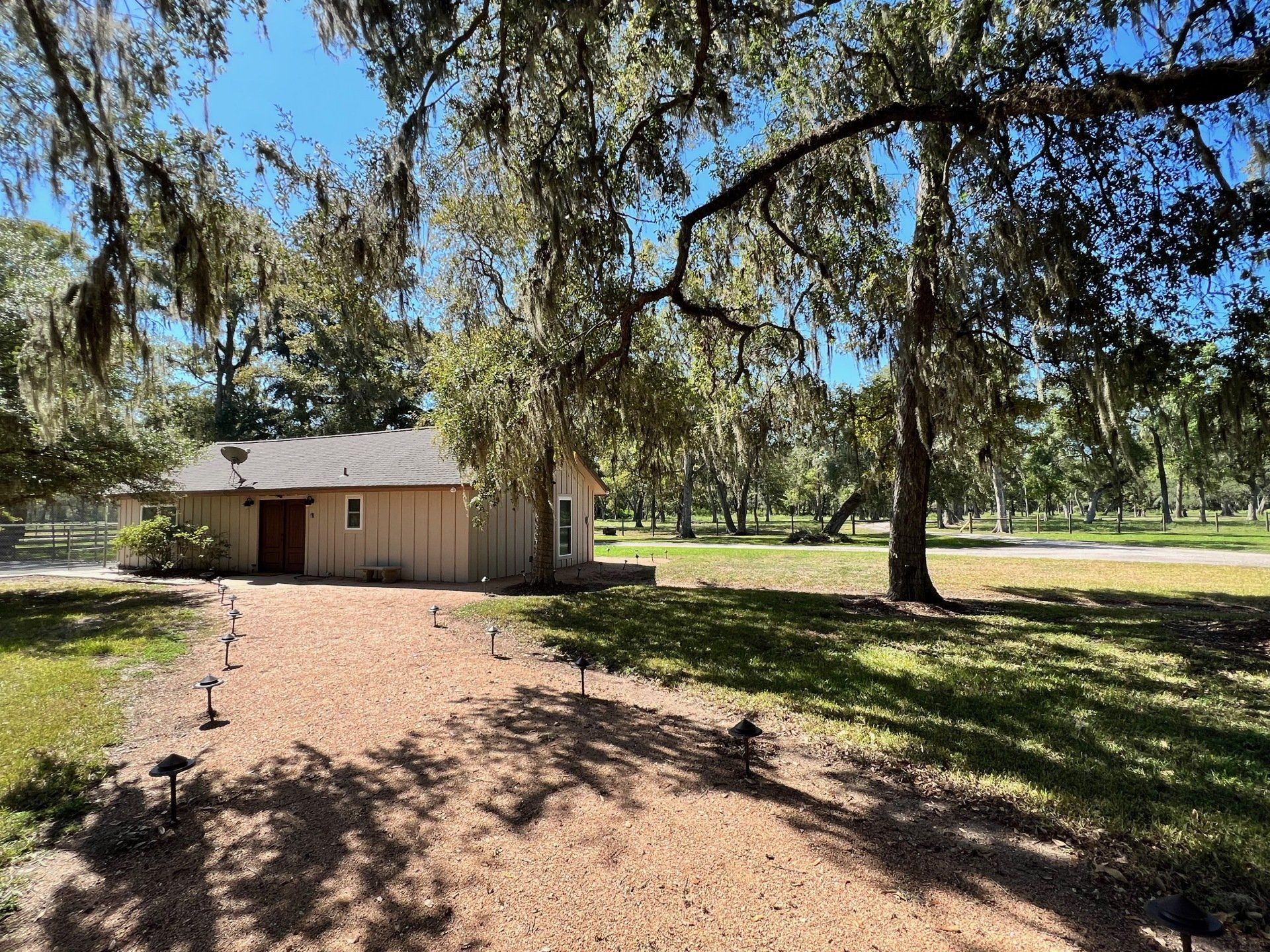 a small house is sitting in the middle of a grassy field surrounded by trees .