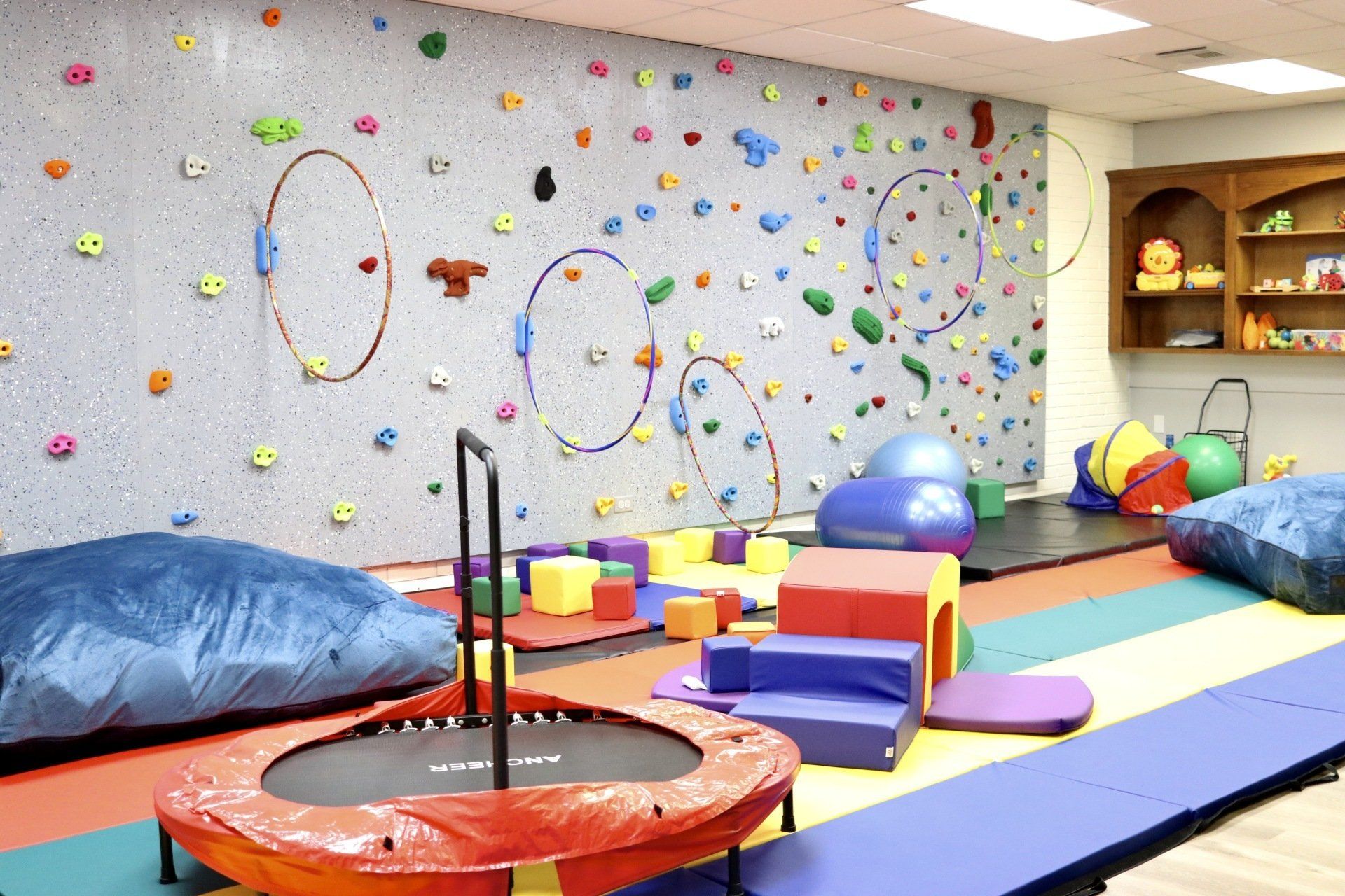 a gym with a climbing wall and a trampoline
