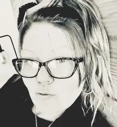 A black and white photo of a woman wearing glasses and a headband.