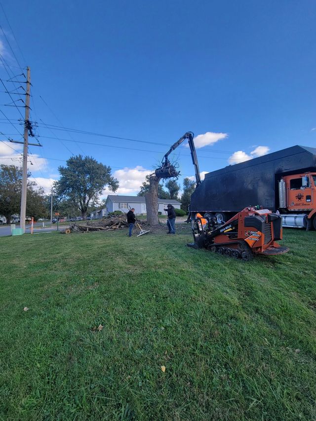 Orange farm equipment on a grassy field near a building under a blue sky