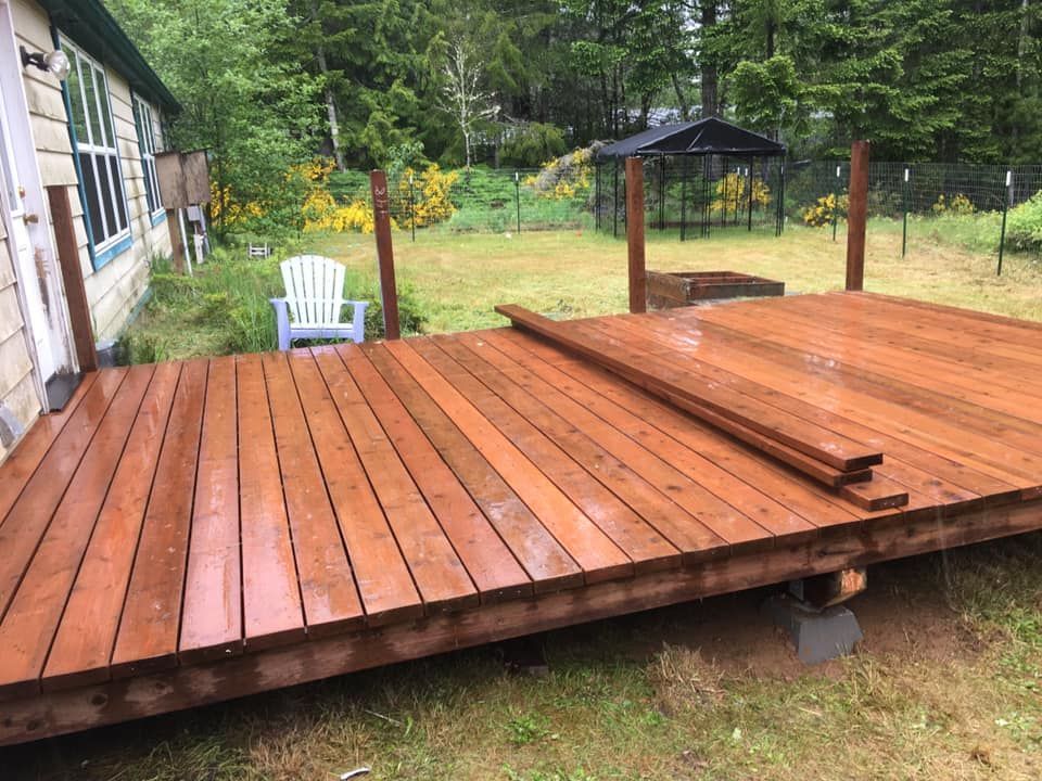A wooden deck is sitting in the grass in front of a house.