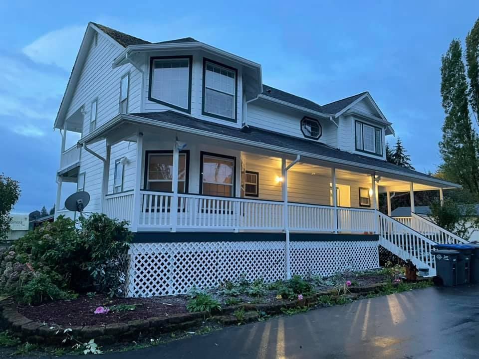 A large white house with a large porch and stairs.