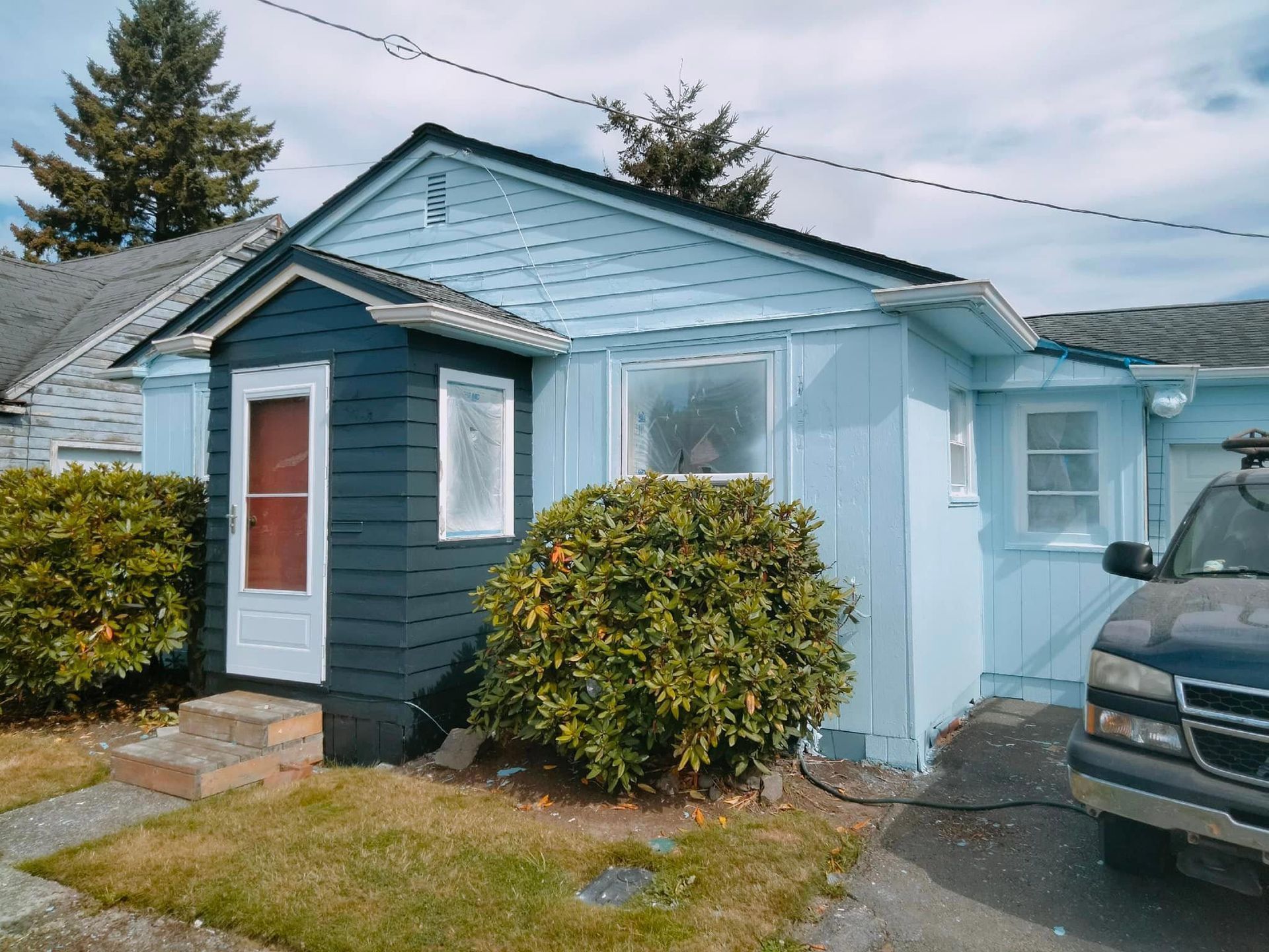 A blue house with a black van parked in front of it