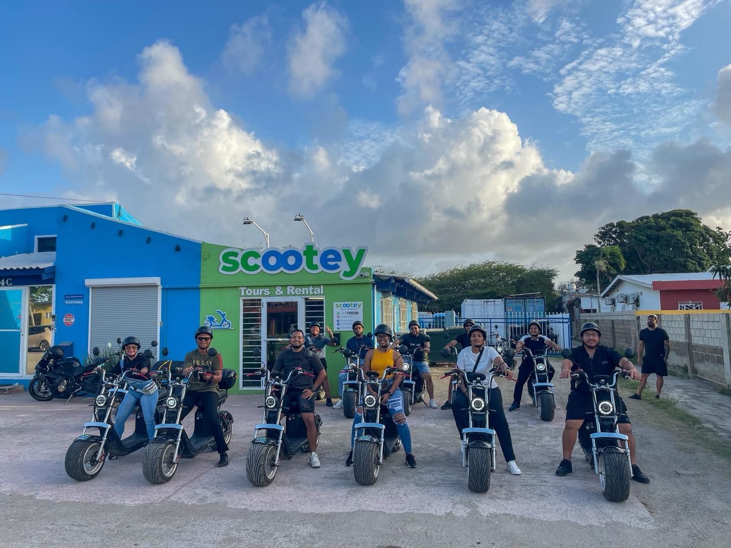 Riders on electric scooters outside the Scootey Aruba shop