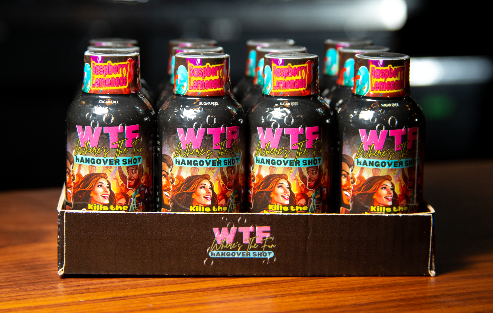 A cardboard tray holding twelve small, black bottles labeled