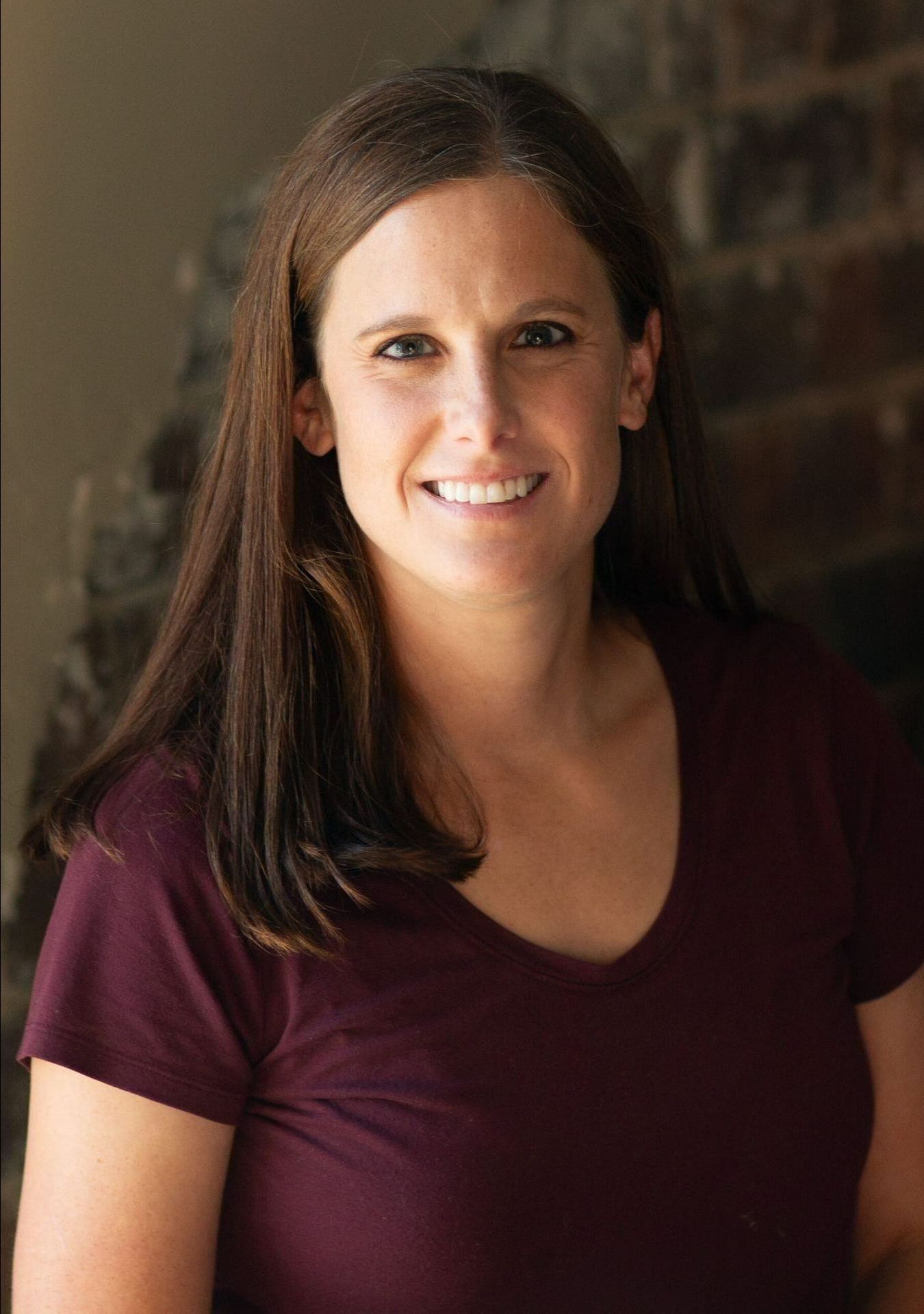 A woman wearing a black jacket and a pink shirt is smiling for the camera.