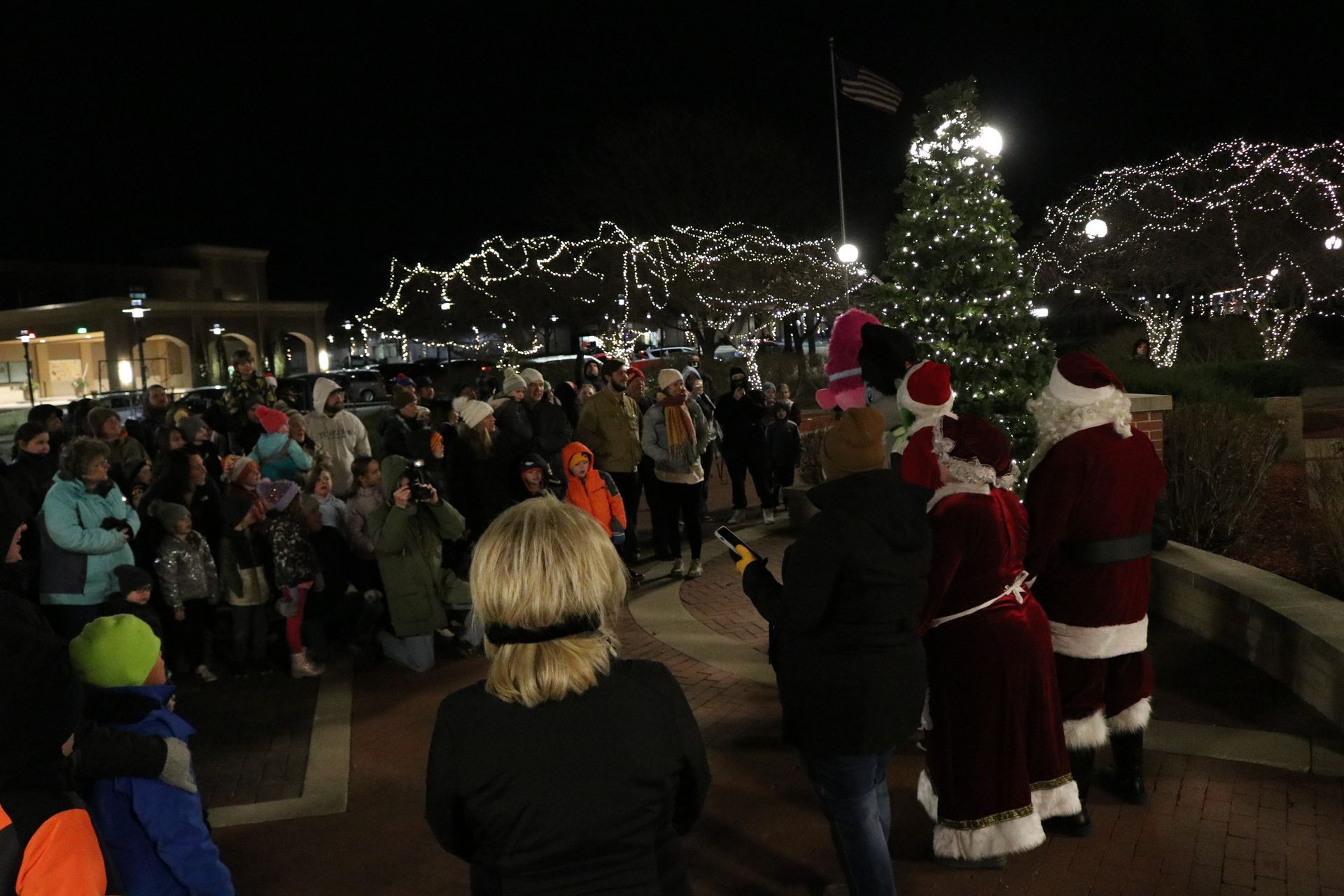 A group of people are standing in front of a christmas tree.