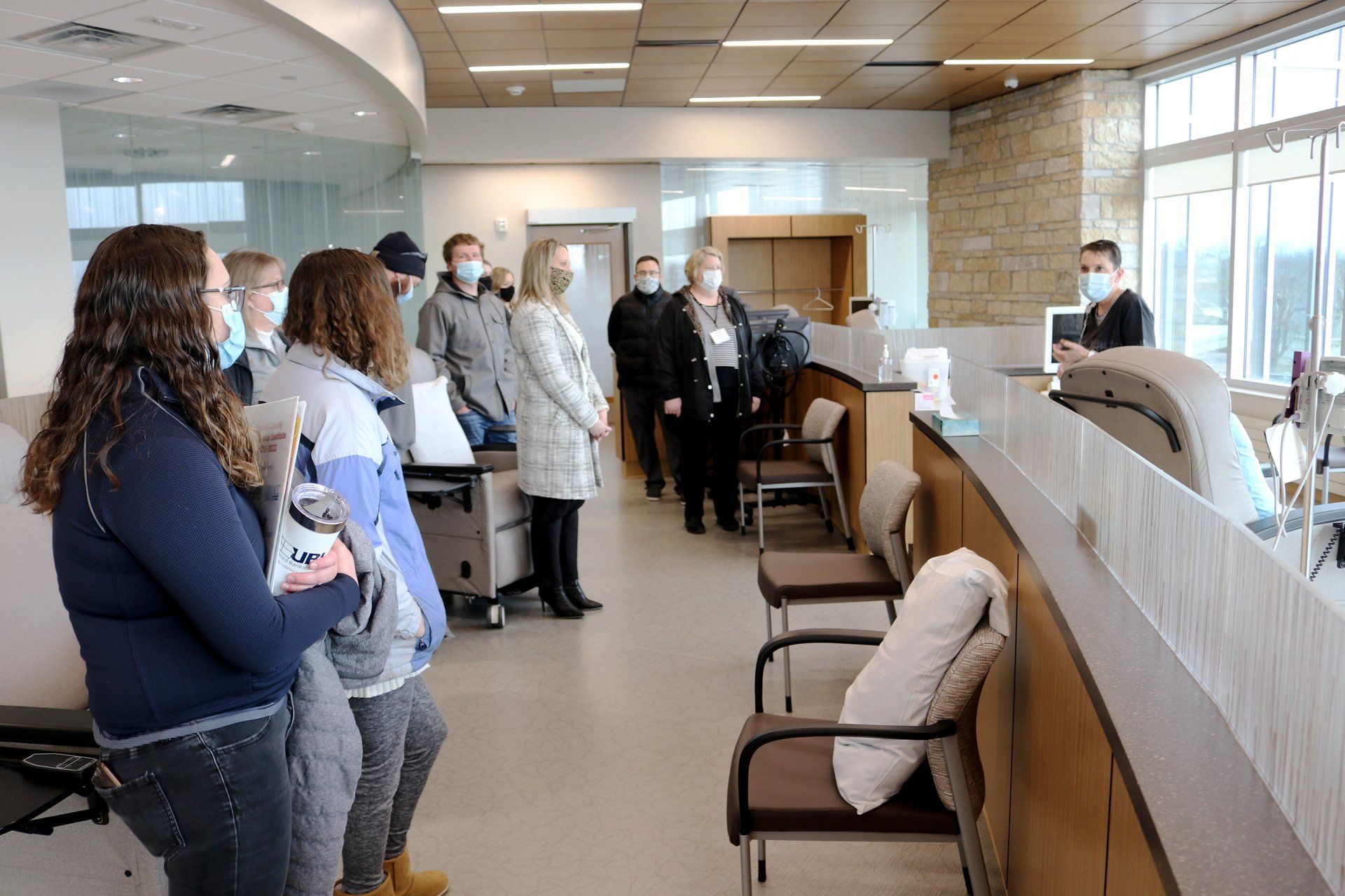 A group of people wearing face masks are standing in a waiting room.