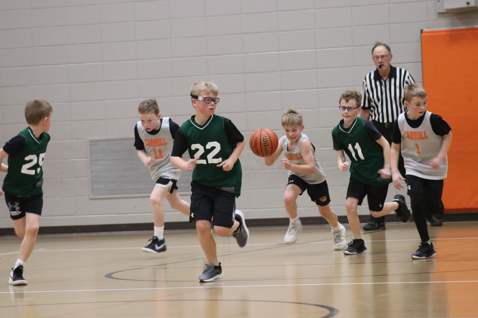 A group of young boys are playing basketball on a court.