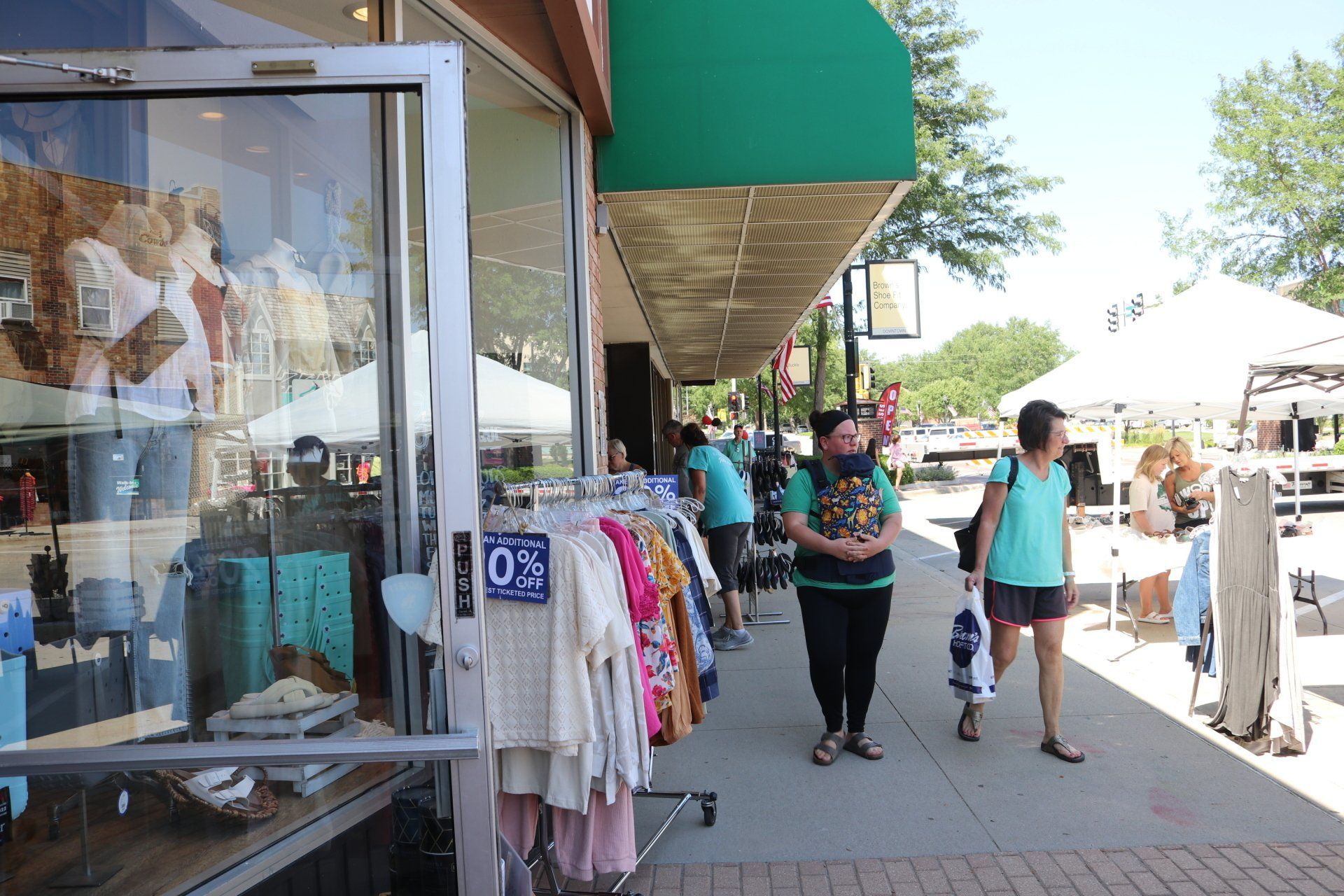 A group of people are walking down a sidewalk in front of a store.