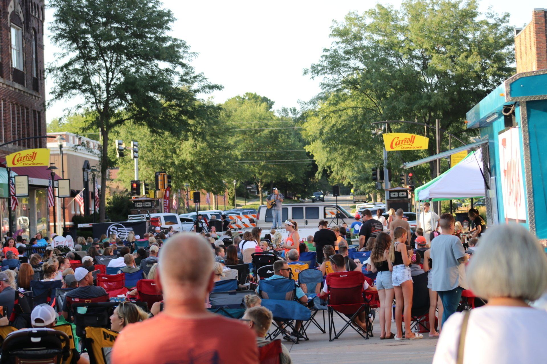 A crowd of people are sitting in chairs on a city street.