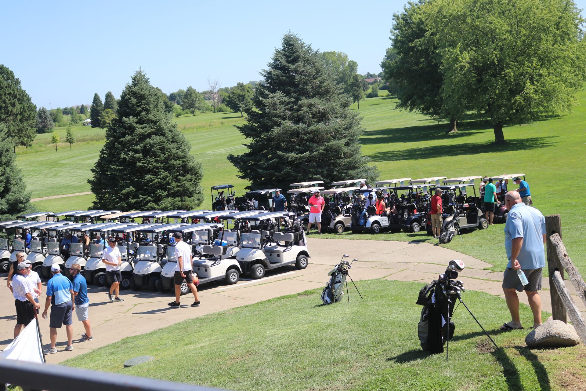 A bunch of golf carts are parked on a golf course