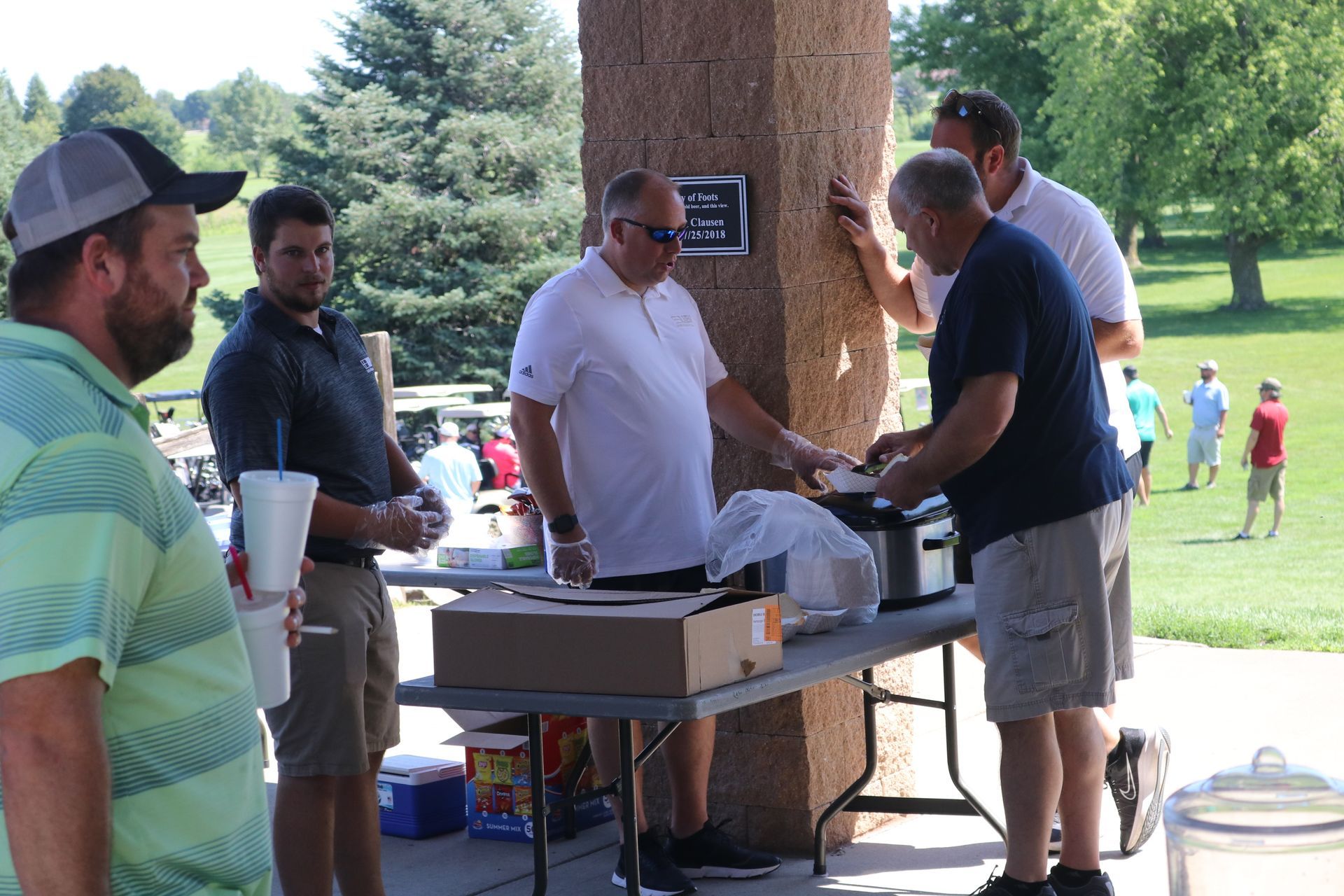A group of men are standing around a table in a park.