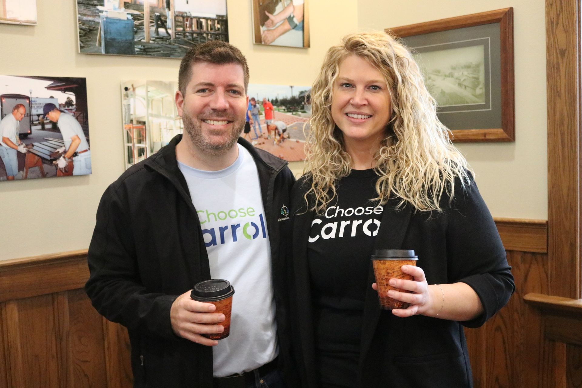 A man and a woman are standing next to each other holding cups of coffee.