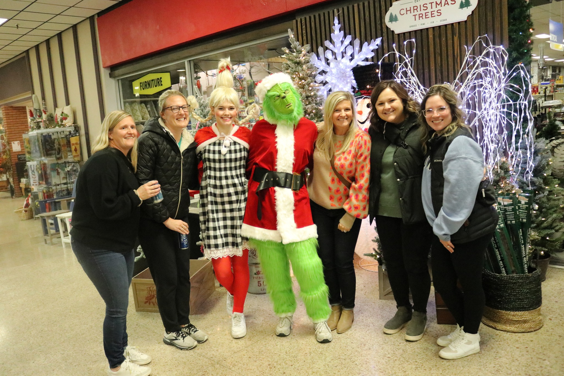 A group of women are posing for a picture with a grinch costume.