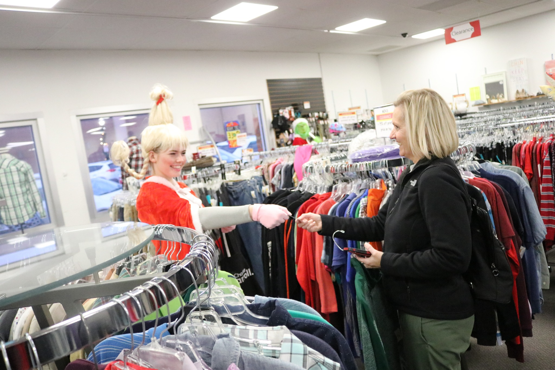 Two women are standing in a clothing store looking at clothes.