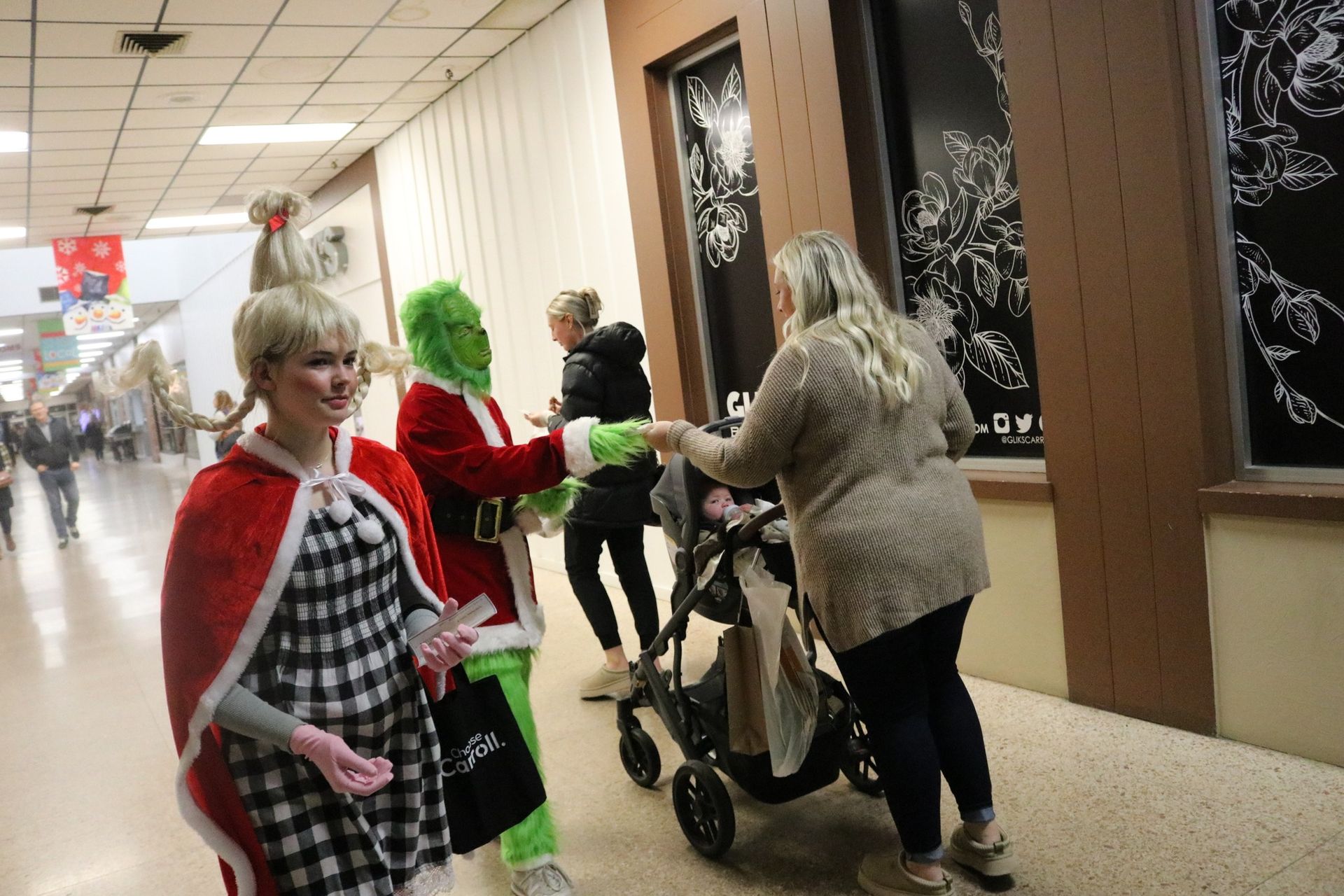 A group of people dressed as the grinch are walking down a hallway.