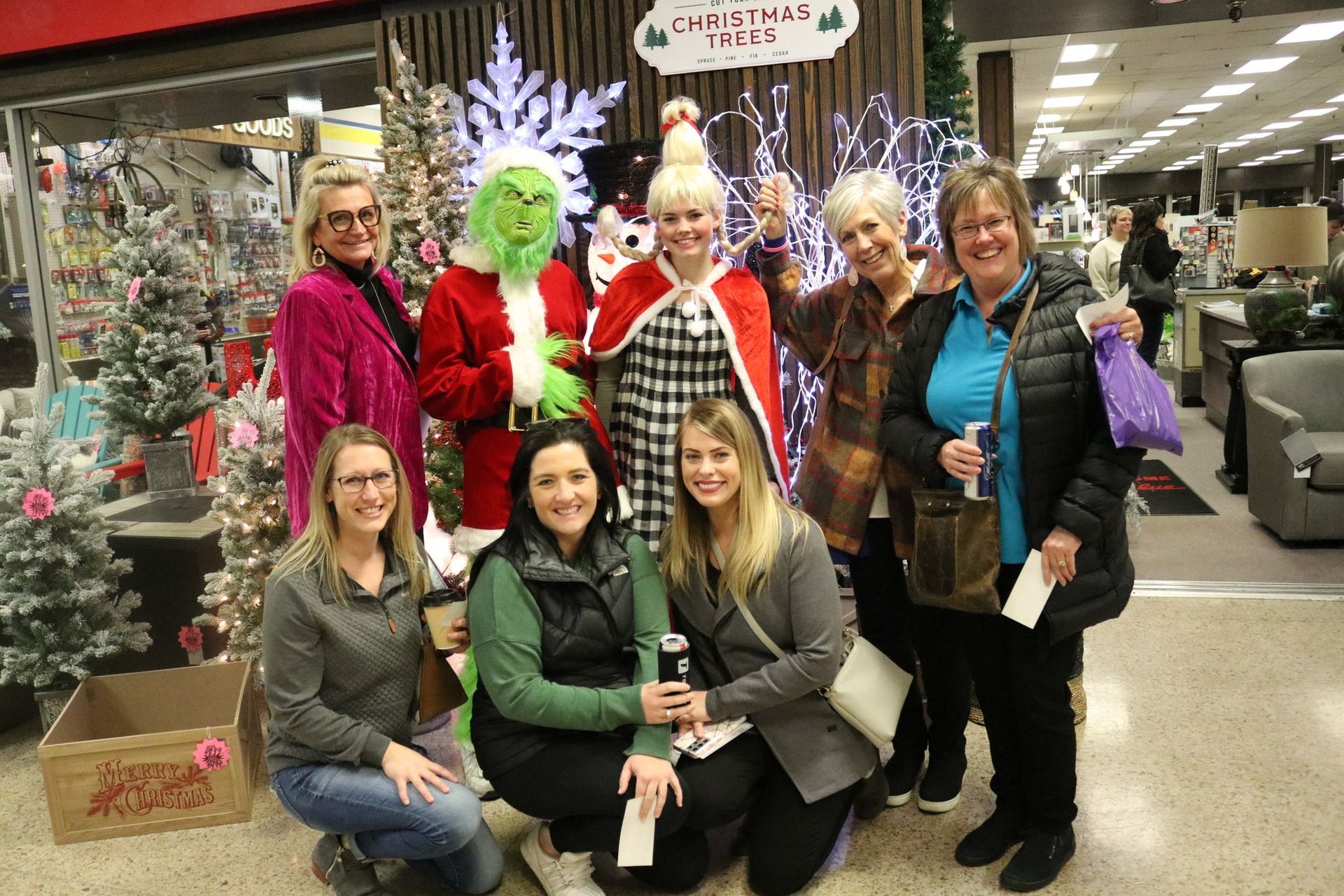 A group of women are posing for a picture with a grinch.