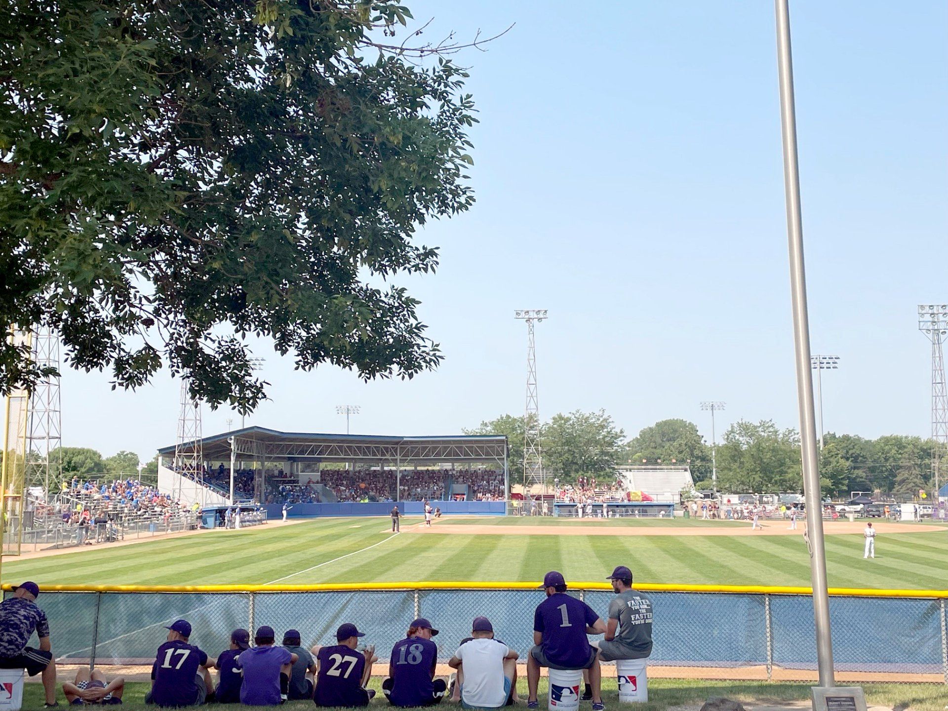 A group of people sitting on stools watching a baseball game