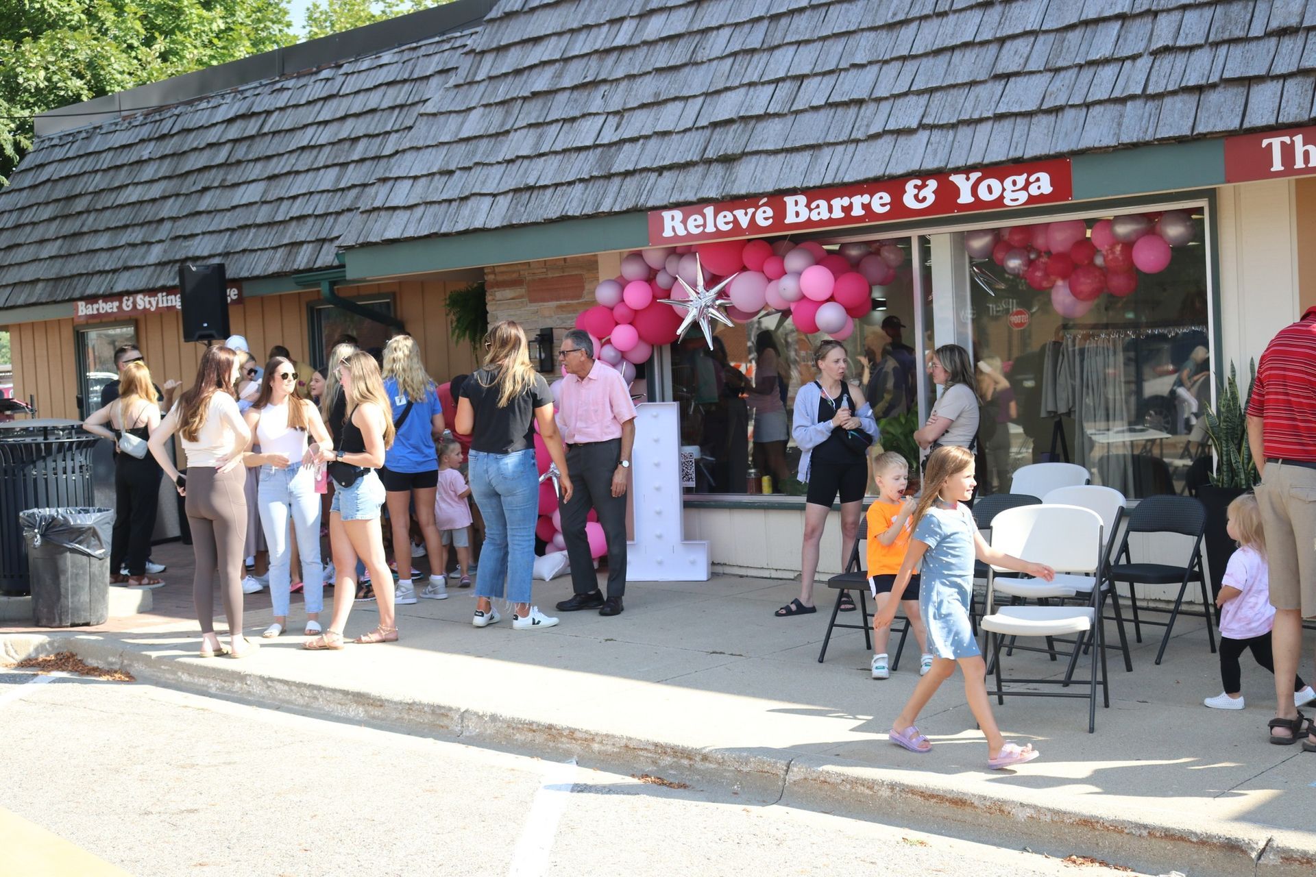 A group of people are standing outside of a store called relieve barre & yoga.