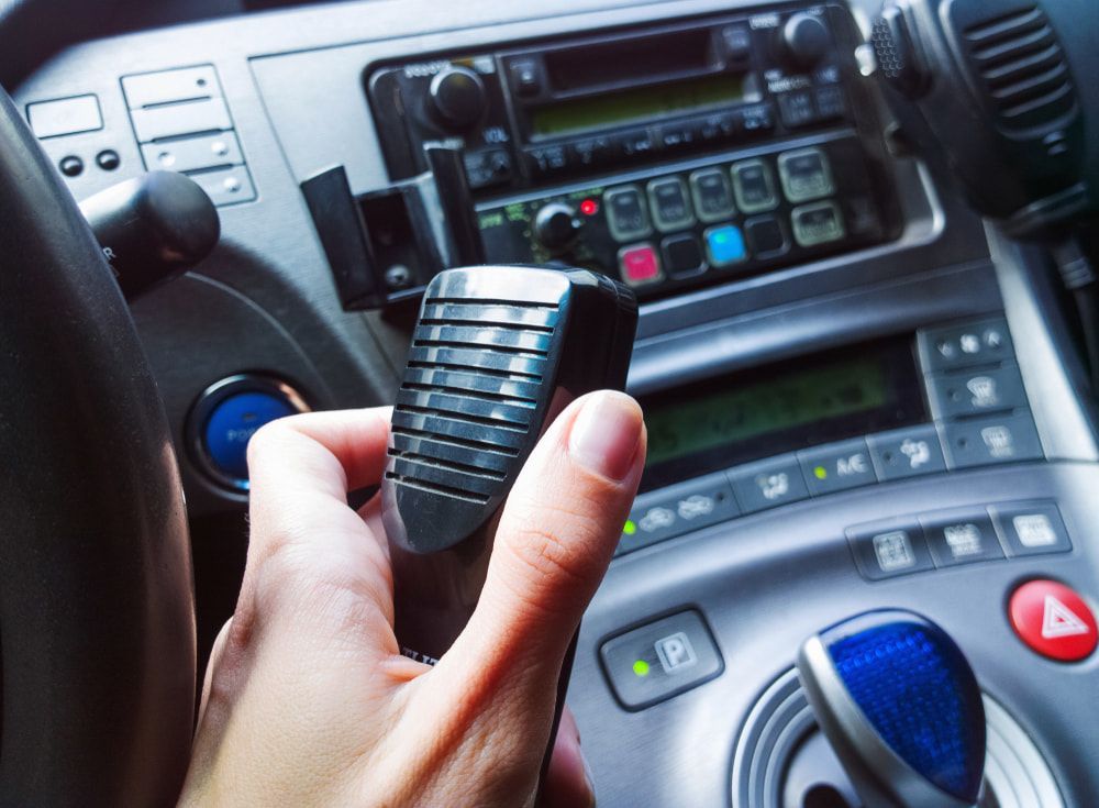 Security guard in a patrol car holding a walkie-talkie microphone — Alarm Monitoring in Mittagong, NSW