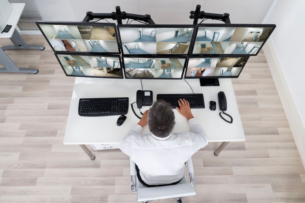 Security guard monitoring CCTV footage at office desk — Alarm Monitoring in Mittagong, NSW