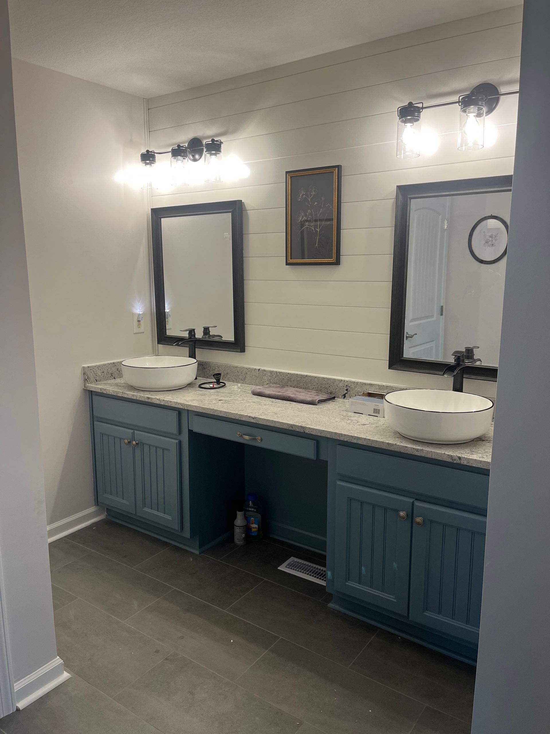 Bathroom vanity with two mirrors, lights, white countertop, and blue cabinets