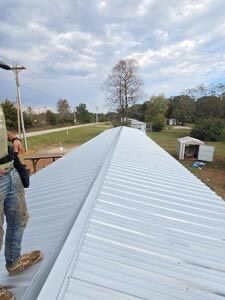 Worker standing on a metal roof during installation on a rural building