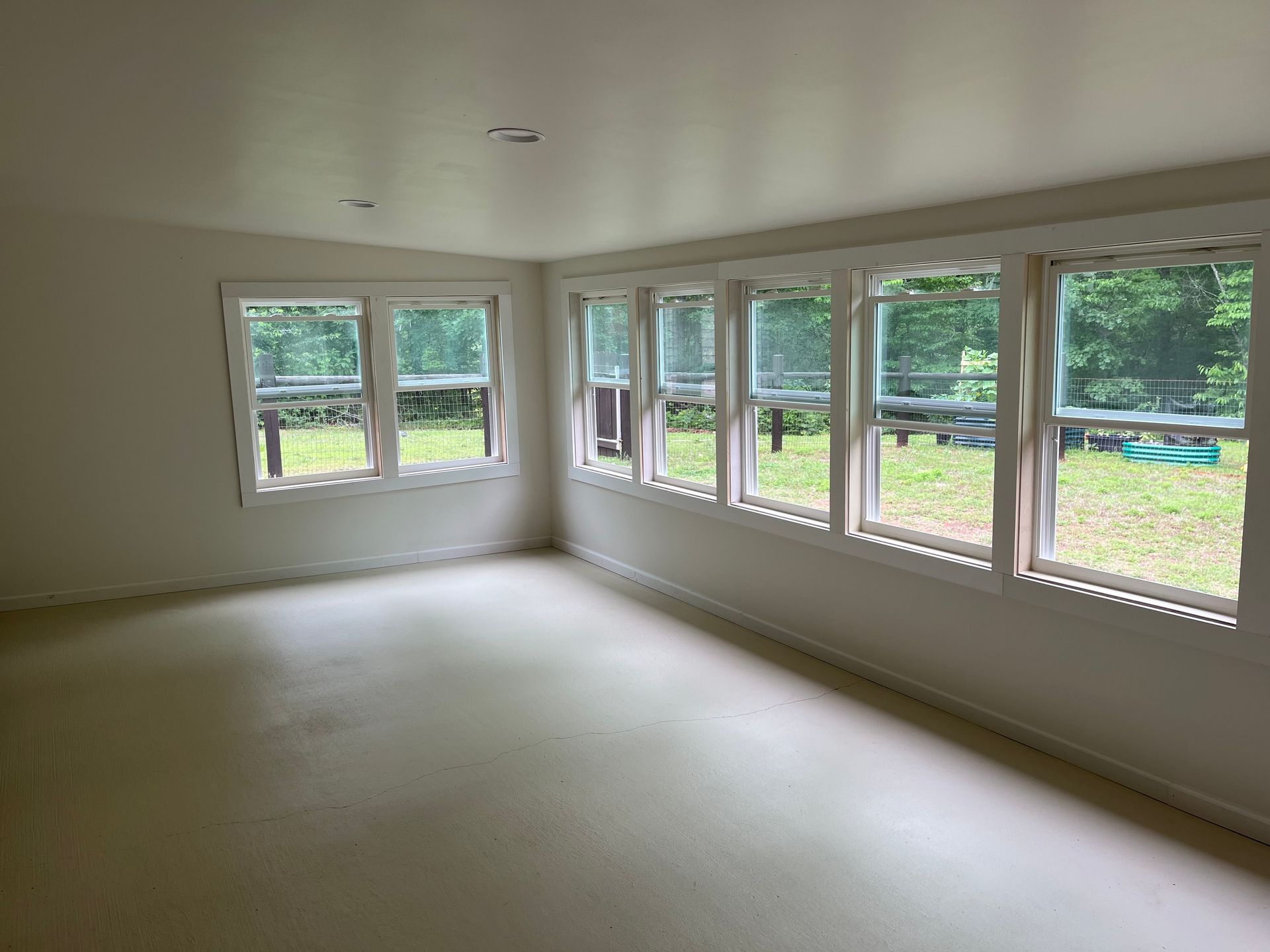 Empty bright room with large windows and light-colored walls and floor
