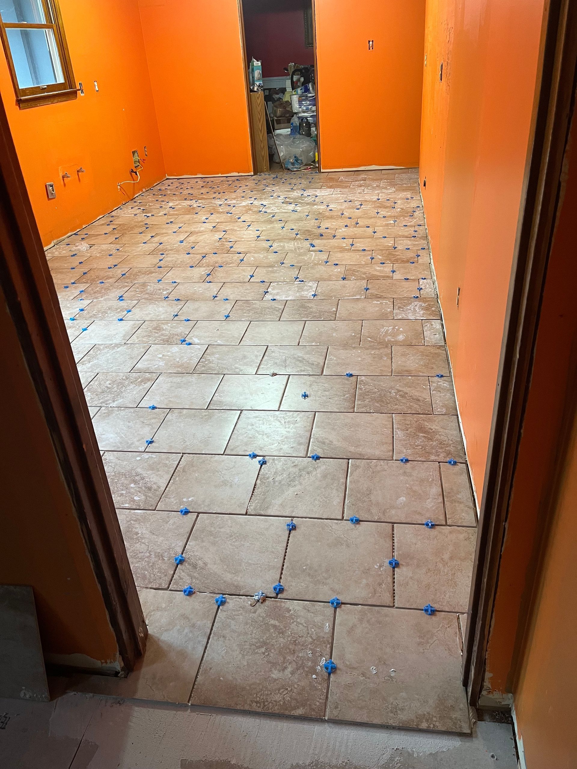 Orange-walled hallway with unfinished tile floor and doorway at the end