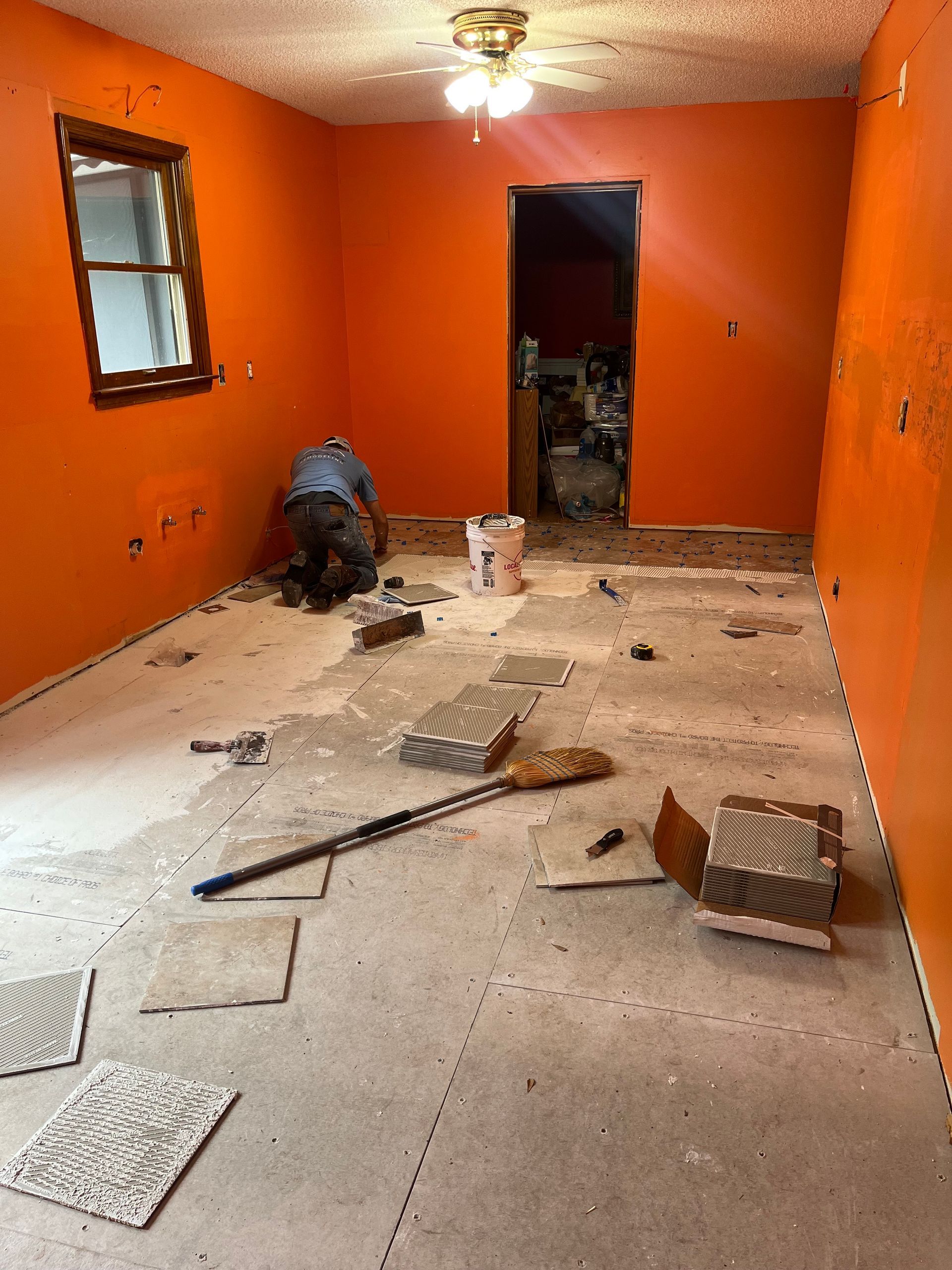 Orange room under renovation with debris and tools scattered across the floor