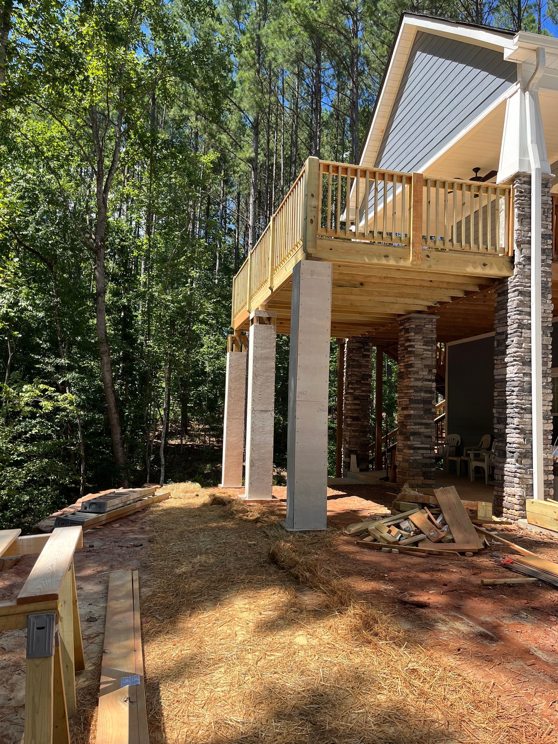 Wooden elevated deck with railings and stairs under construction in a wooded backyard