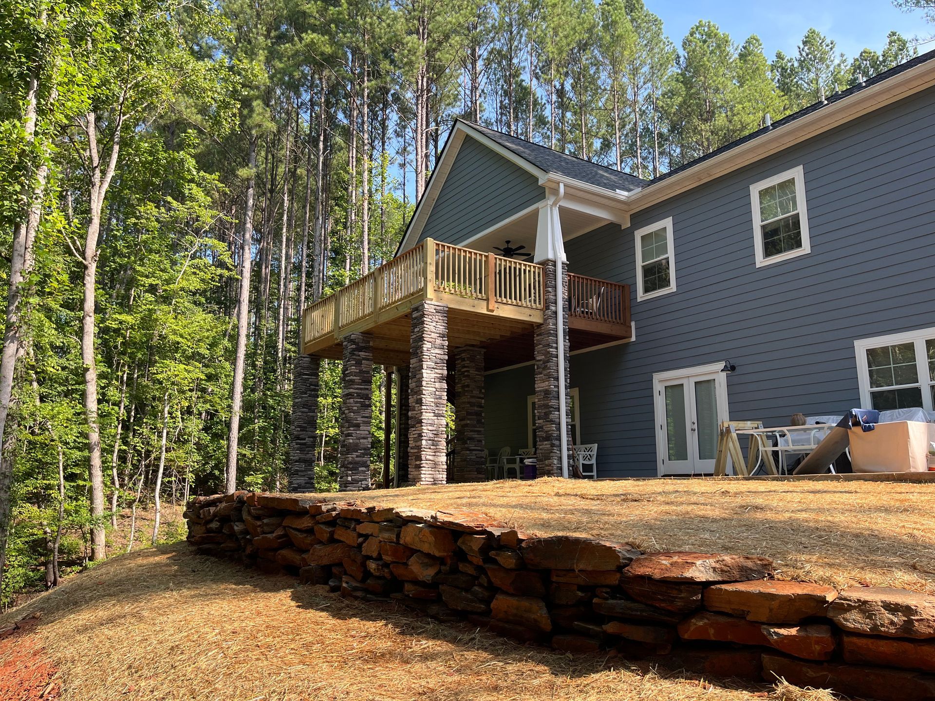 House with wooden deck on a sloped, wooded backyard