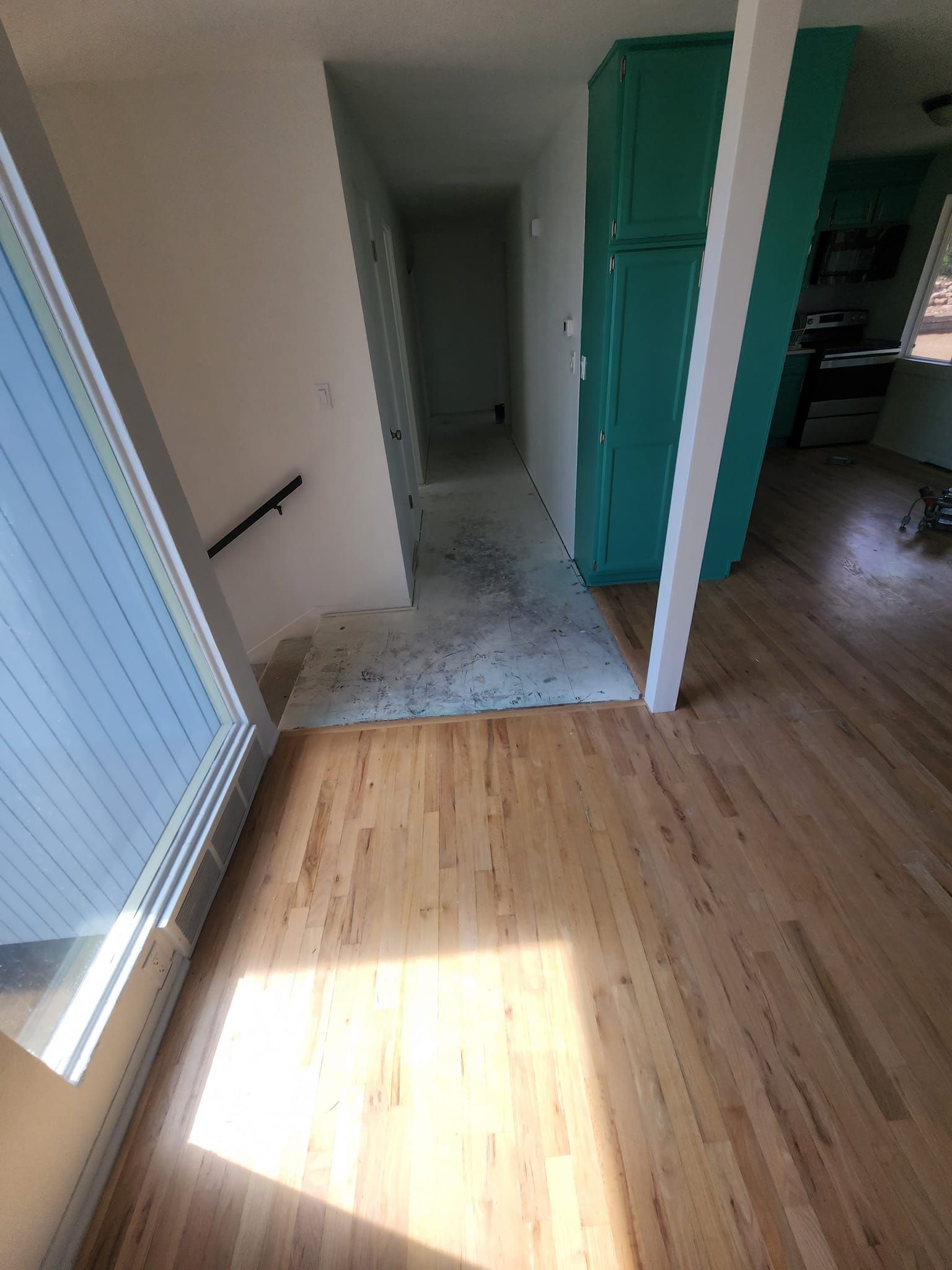 A hallway with hardwood floors and a blue cabinet in a house.