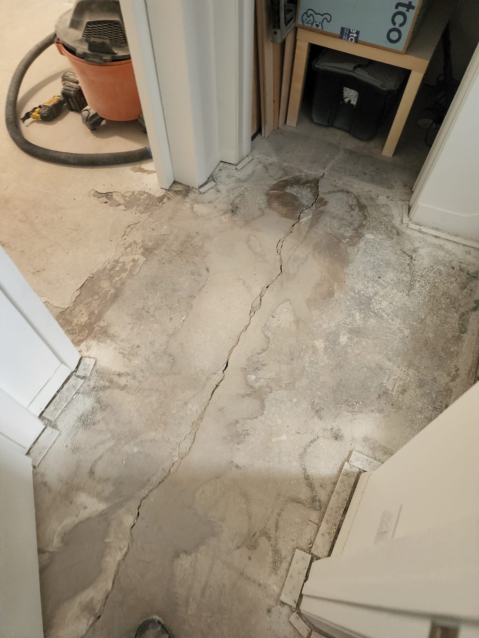 A cracked concrete floor in a room with a vacuum cleaner.