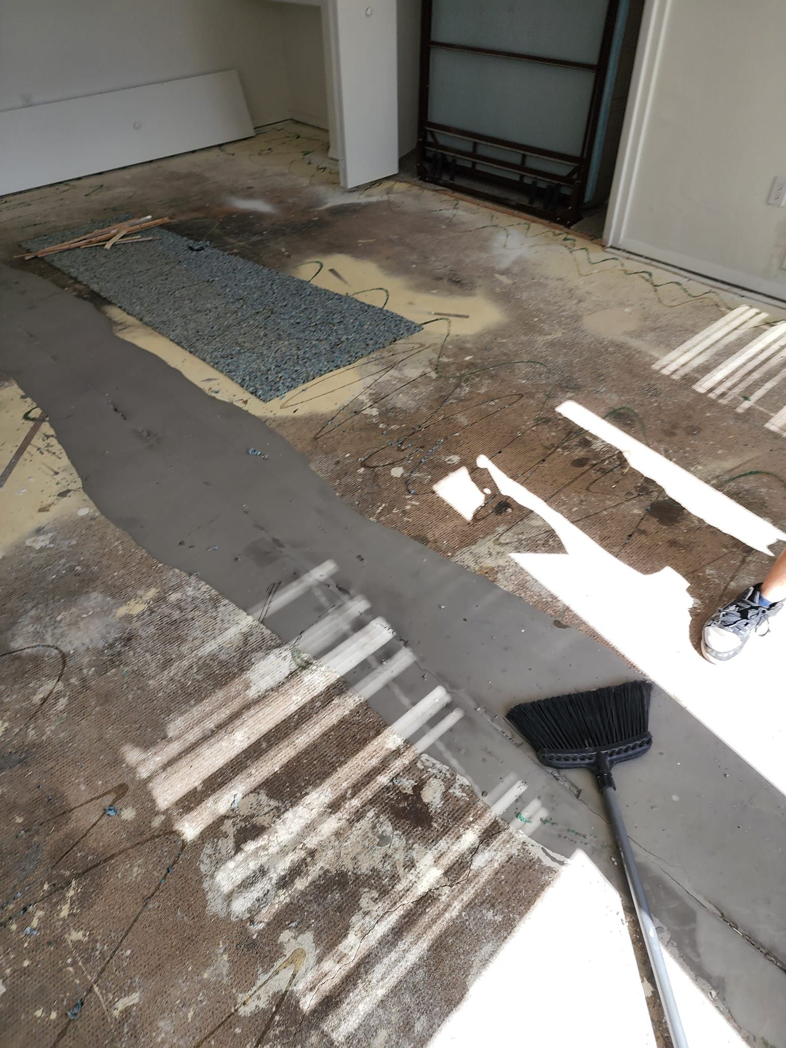 A person is cleaning a dirty floor with a broom.