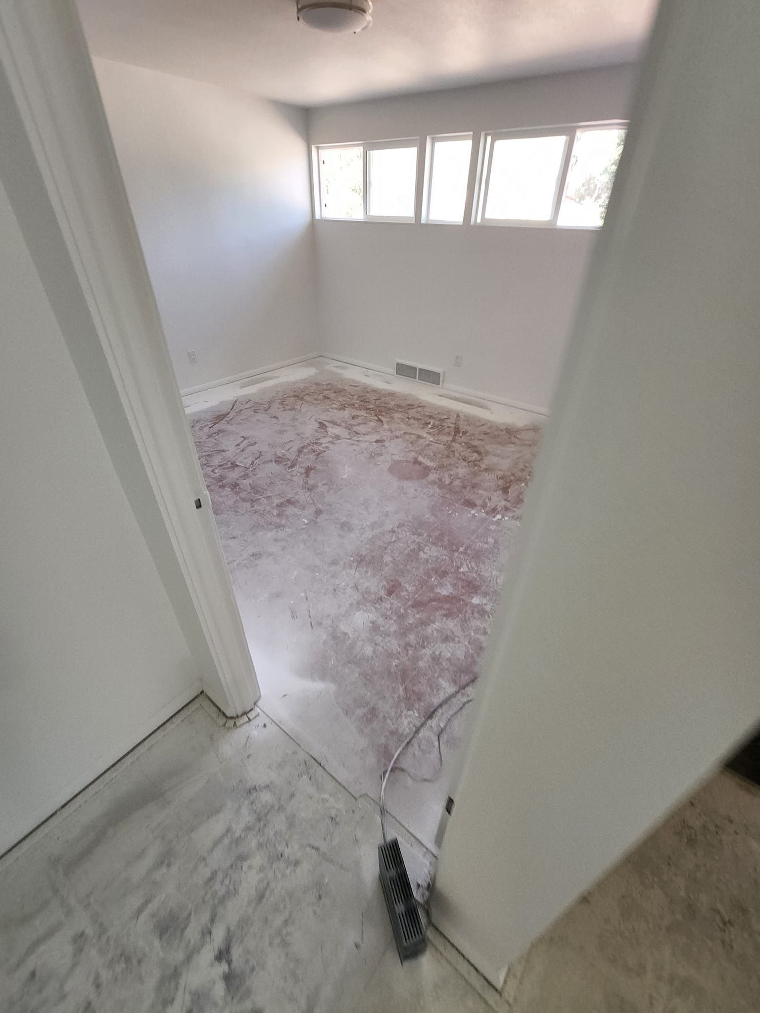 A room with a dirty floor and a broom on the floor.