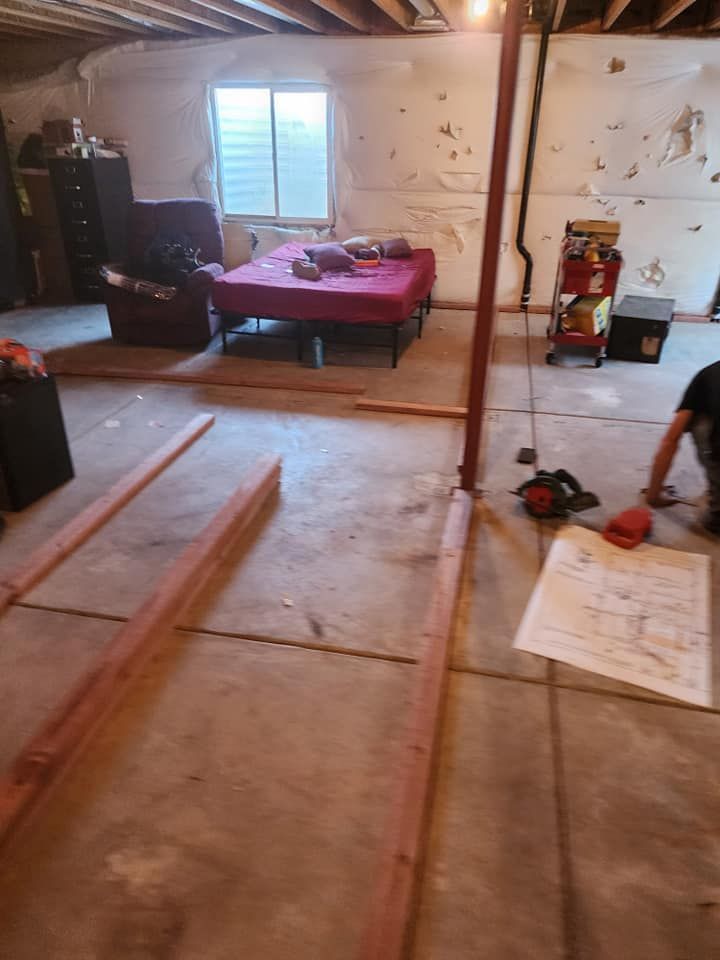 A man is working on the floor of a basement.