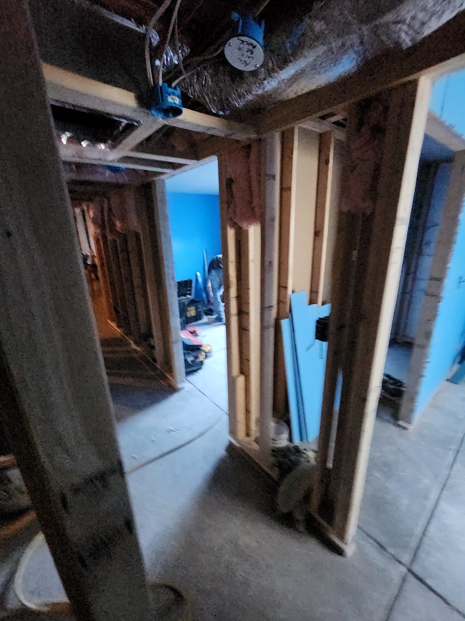 A room in a house under construction with wooden walls and a blue wall.