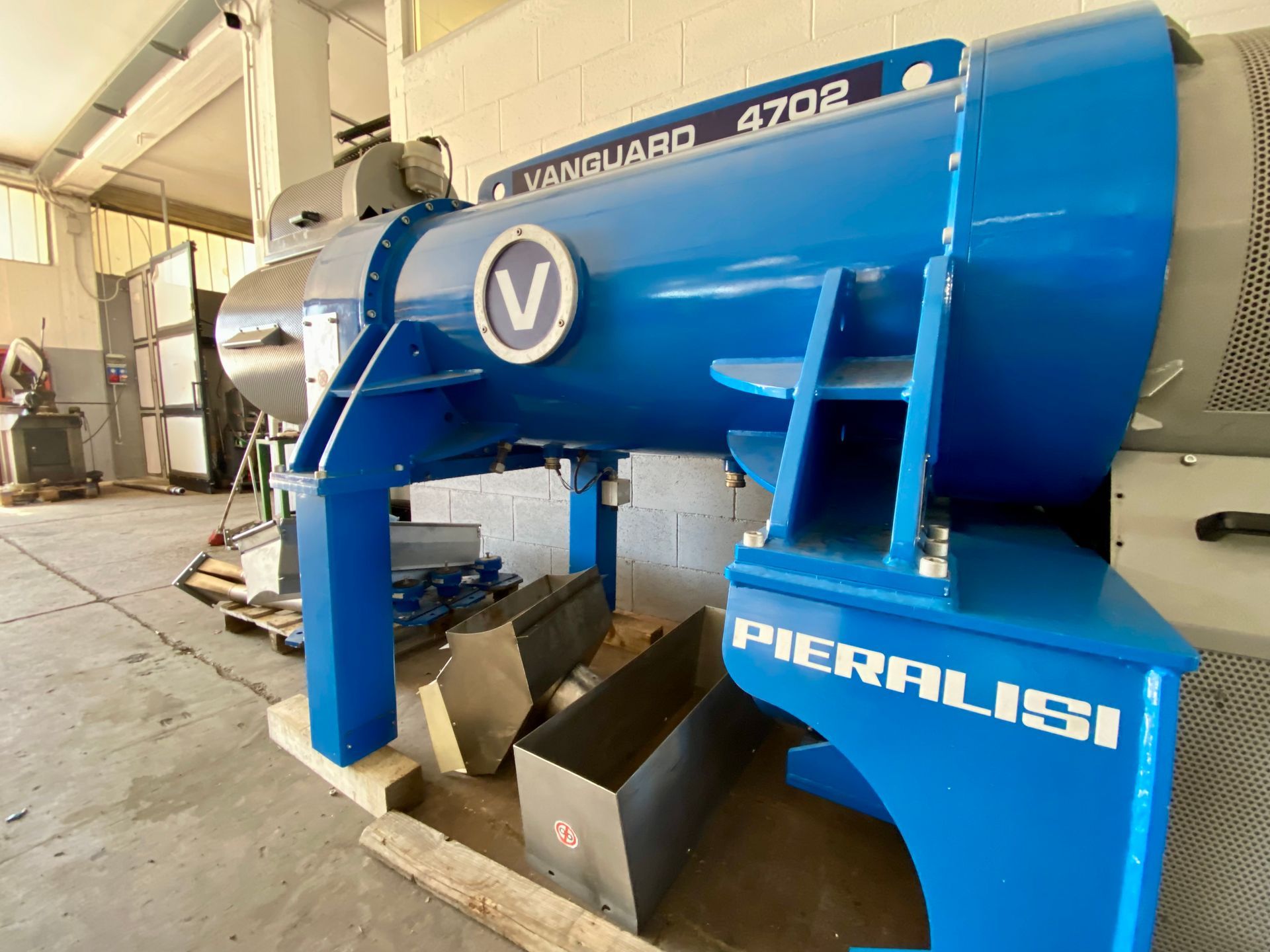 Macchinario industriale blu in un'officina con grande tamburo cilindrico e marchio bianco