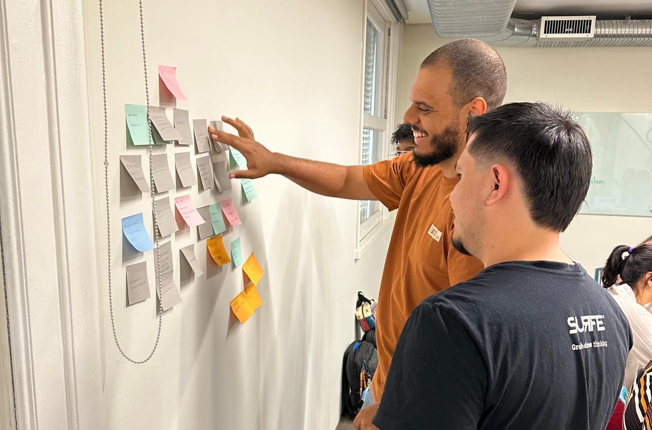 reunião de card sorting, dois homens em frente a uma parede branca com post-its coloridos