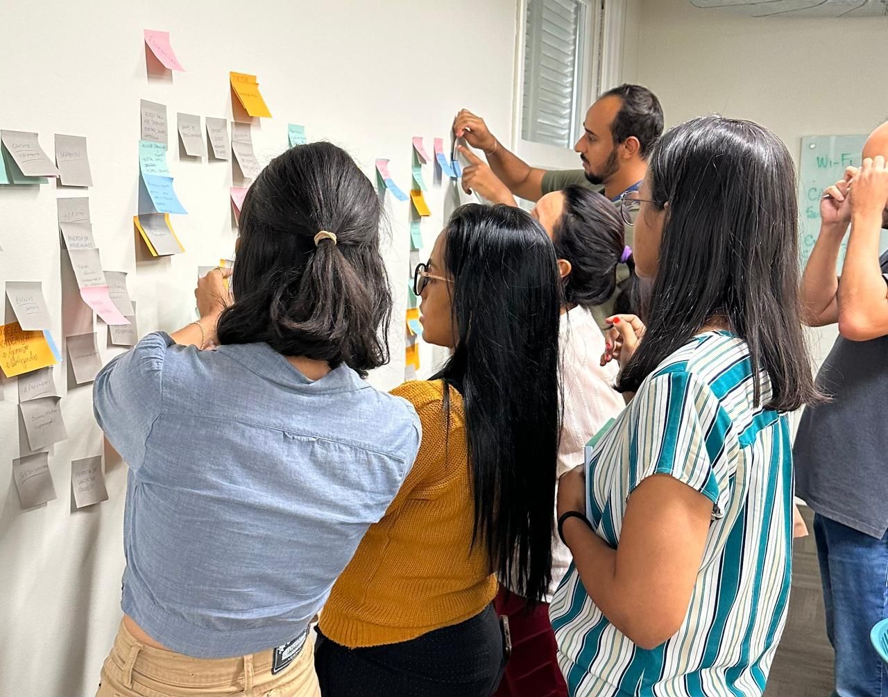 card sorting, um grupo de pessoas olhando para uma parede com post-its
