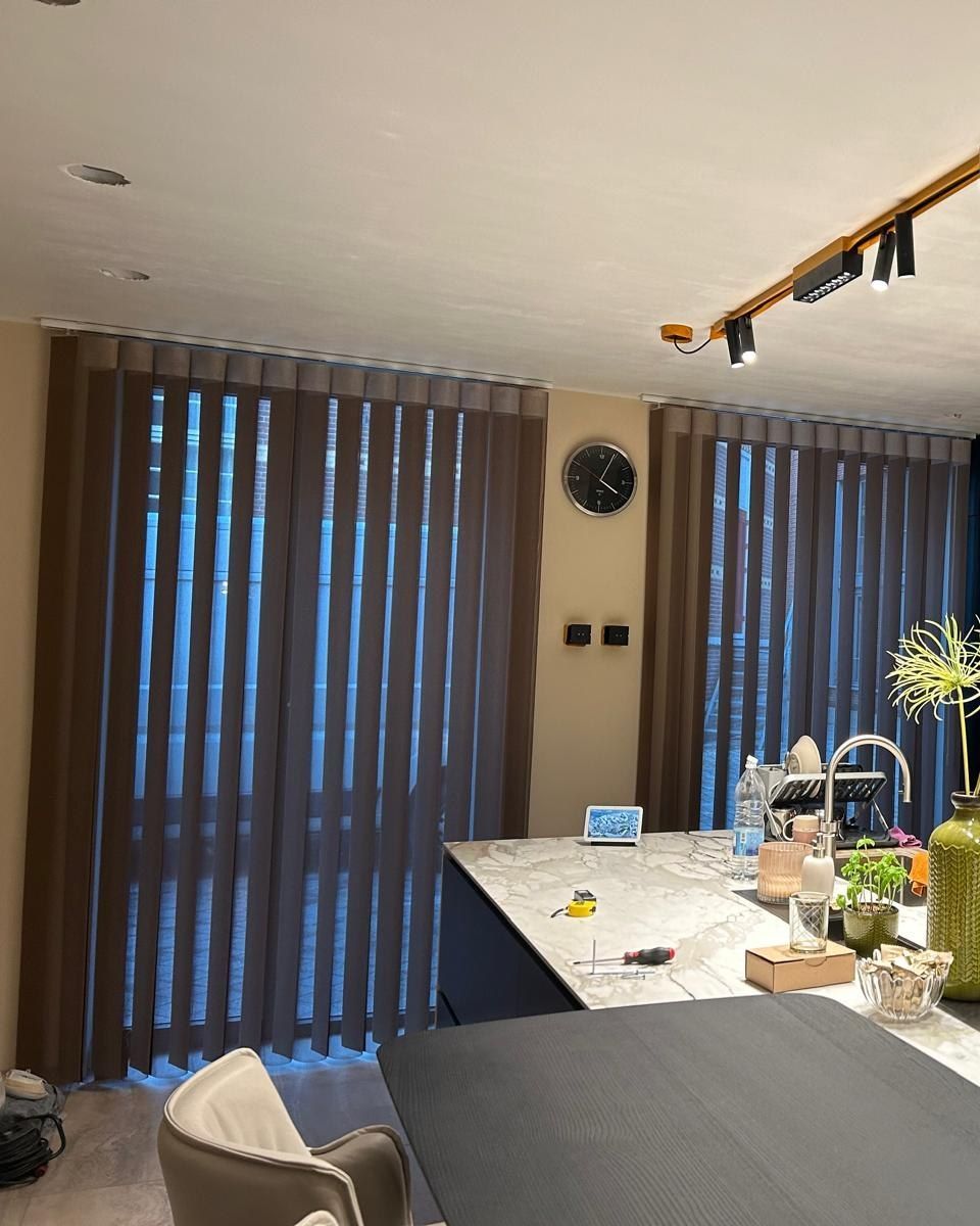 Cucina moderna con ampie finestre con tende, isola in marmo e lampade a sospensione sopra il bancone.