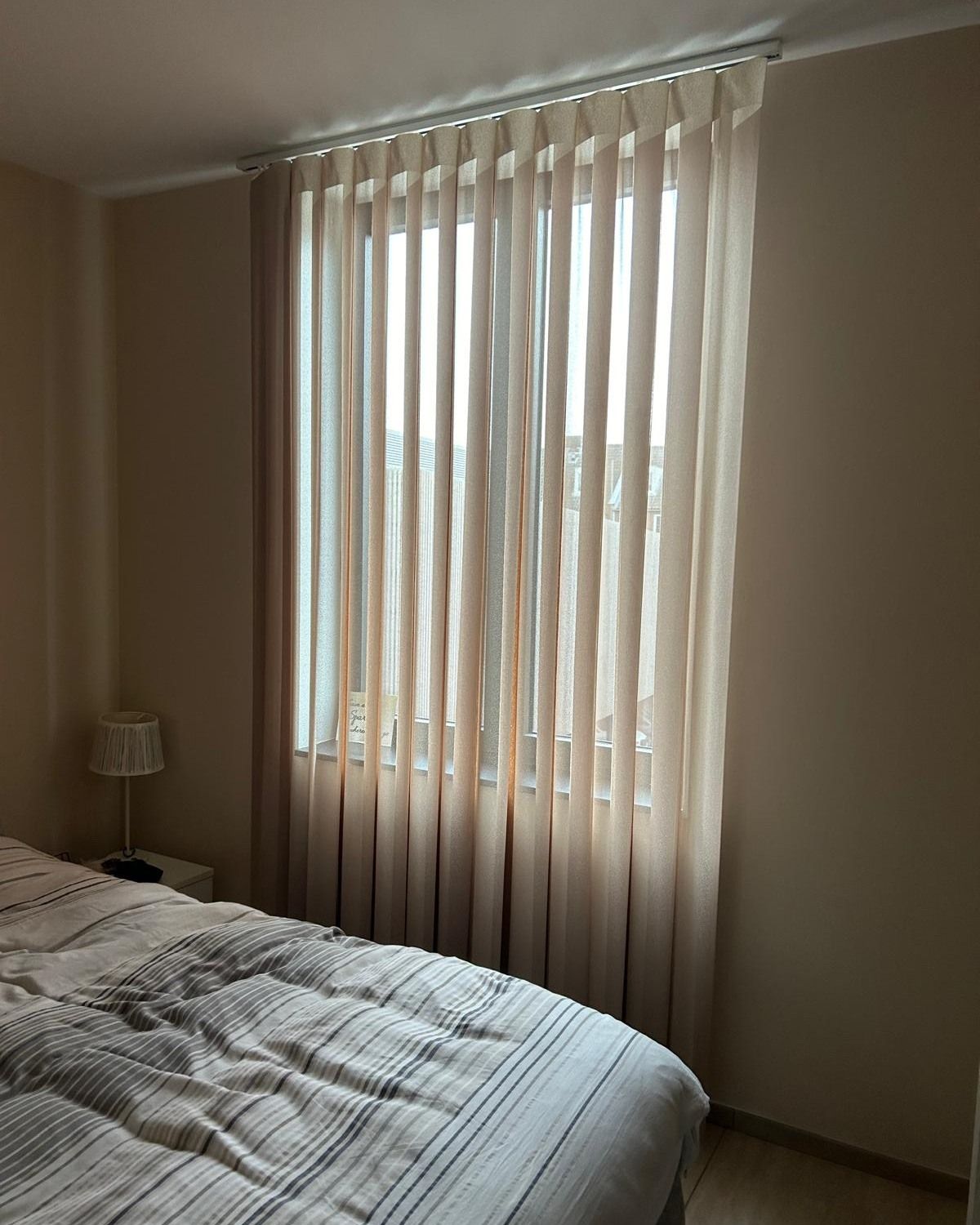Camera da letto con un letto ben rifatto e tende trasparenti su una finestra luminosa